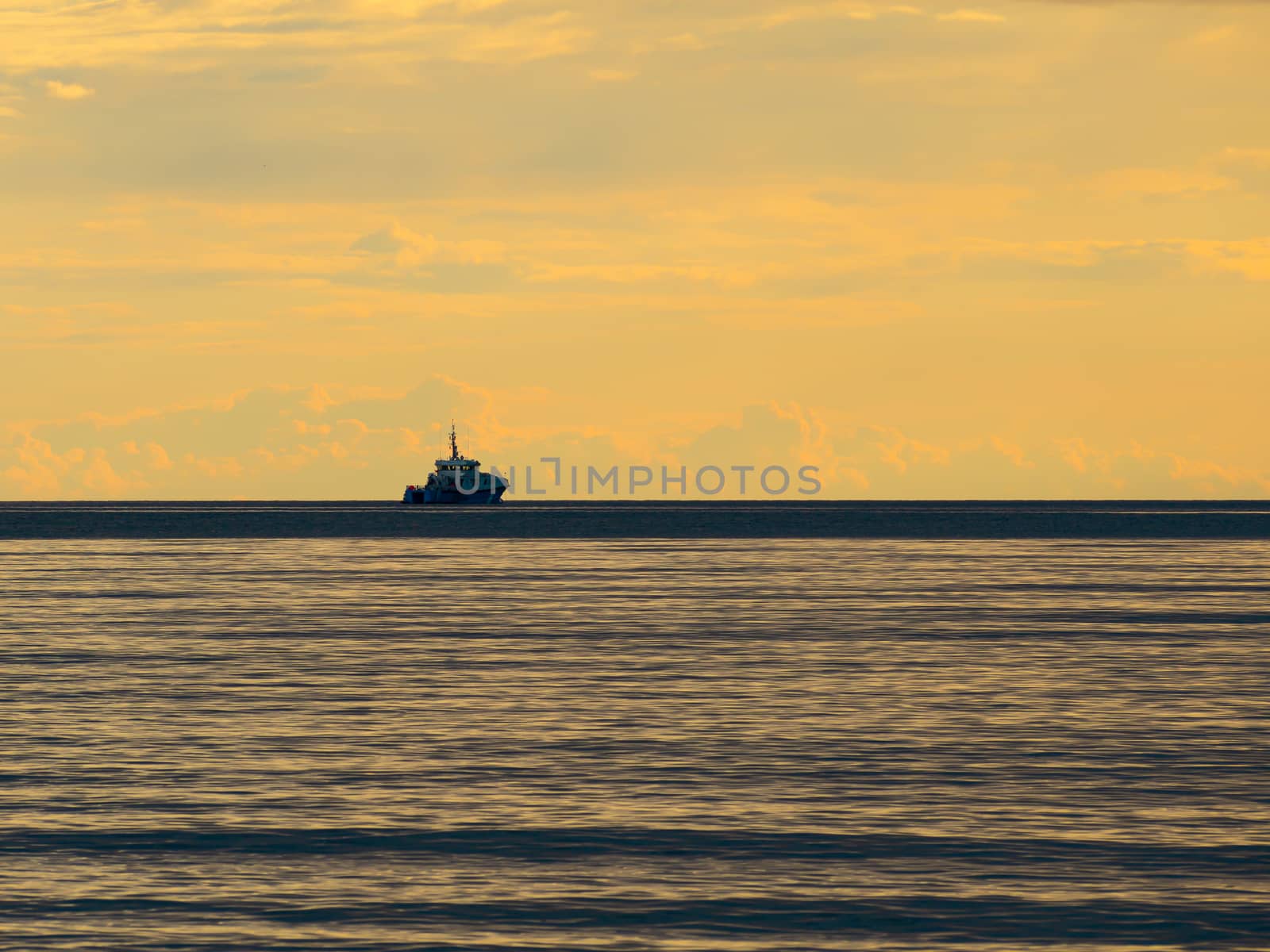 One small fishing boat heading out on the foggy ocean at dawn. Boat on the background of sunset. The Baltic Sea close up, stormy dramatic dark clouds. The Vacation, summer concept