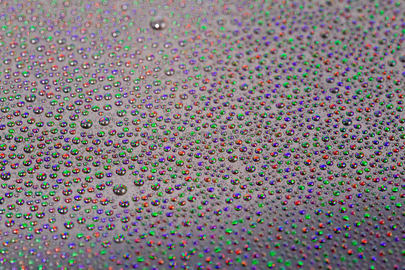 many small water drops on the surface of cellphone hydriphobic coated glass screen, close-up with selective focus and visible subpixel rgb triads