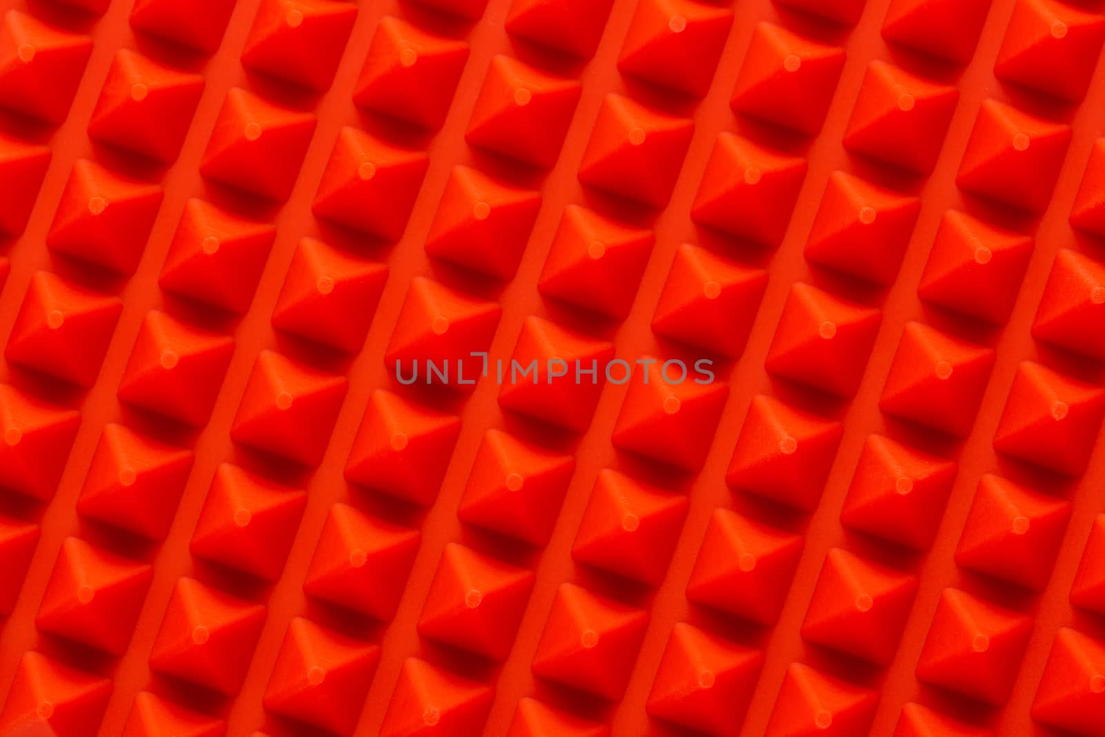 abstract red silicone pyramids array close-up background.