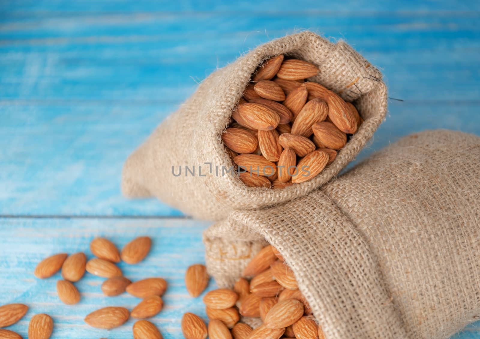 Almond in cloth bag on blurred wooden table background