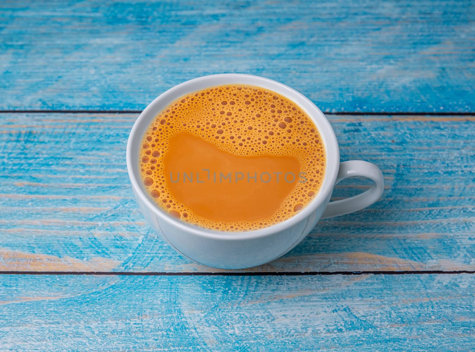 Hot milk tea, in a white cup on wooden table background, Hot tea with milk sweet drink