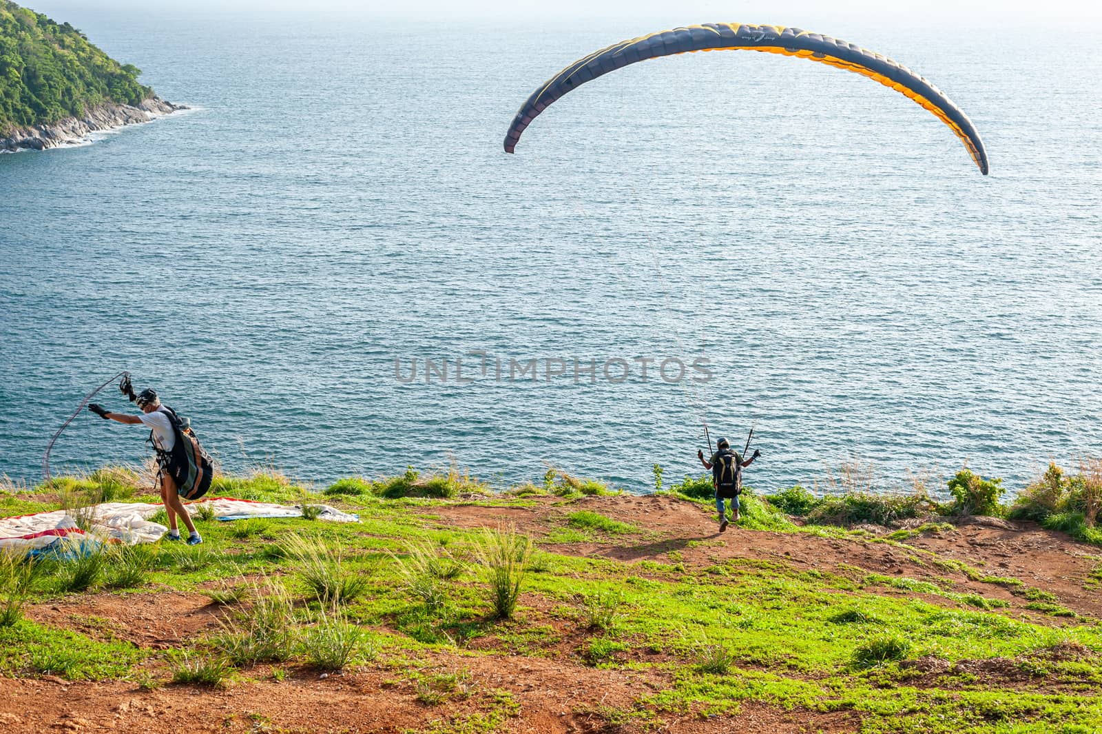 Some people with parachute sport extreme on island sunset in twilight