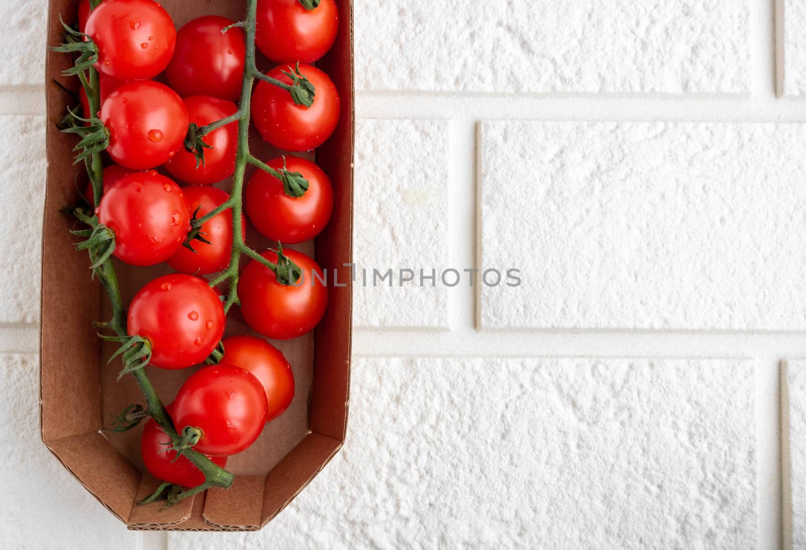 Cherry tomatoes on a branch in eco-friendly packaging. Space for your text.