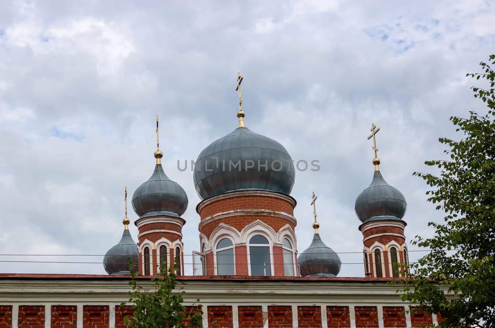 Grey domes with crosses of the Orthodox Church against a cloudy blue sky