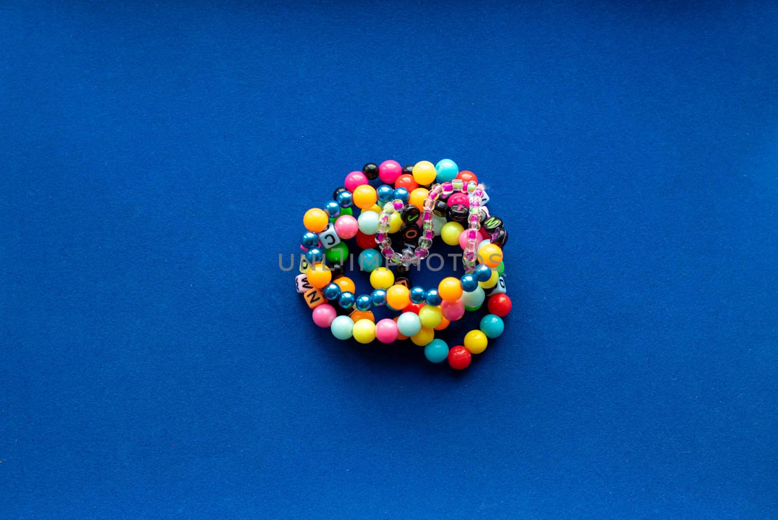 Eight multi-colored bracelets arranged in a flower shape on a blue background. Bracelet with beads. by lapushka62