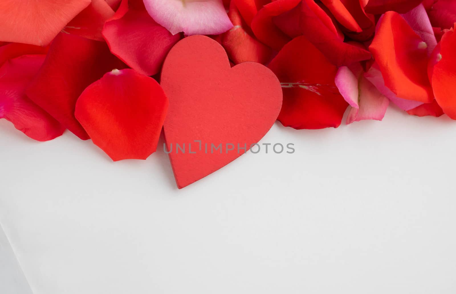 On the red rose petals is a red wooden heart.Concept of mother's Day, family Day, Valentine's Day, March 8