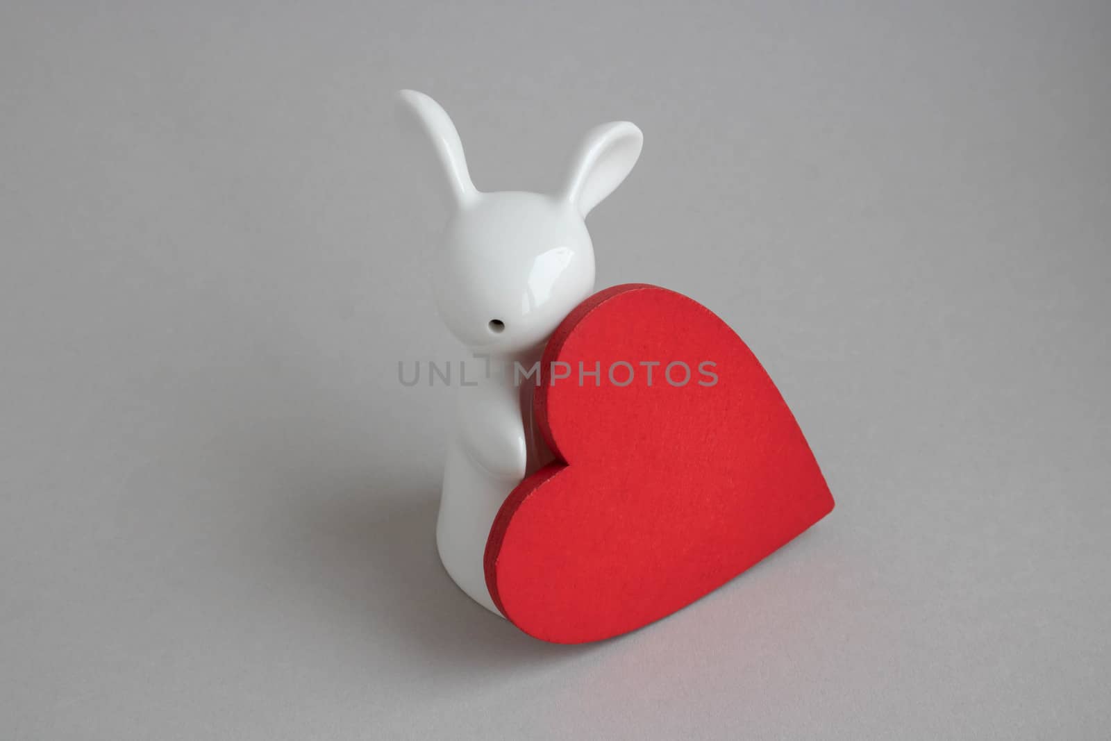 Beautiful ceramic rabbit on white background. statuette of a white rabbit with a red heart.Easter decor by lapushka62