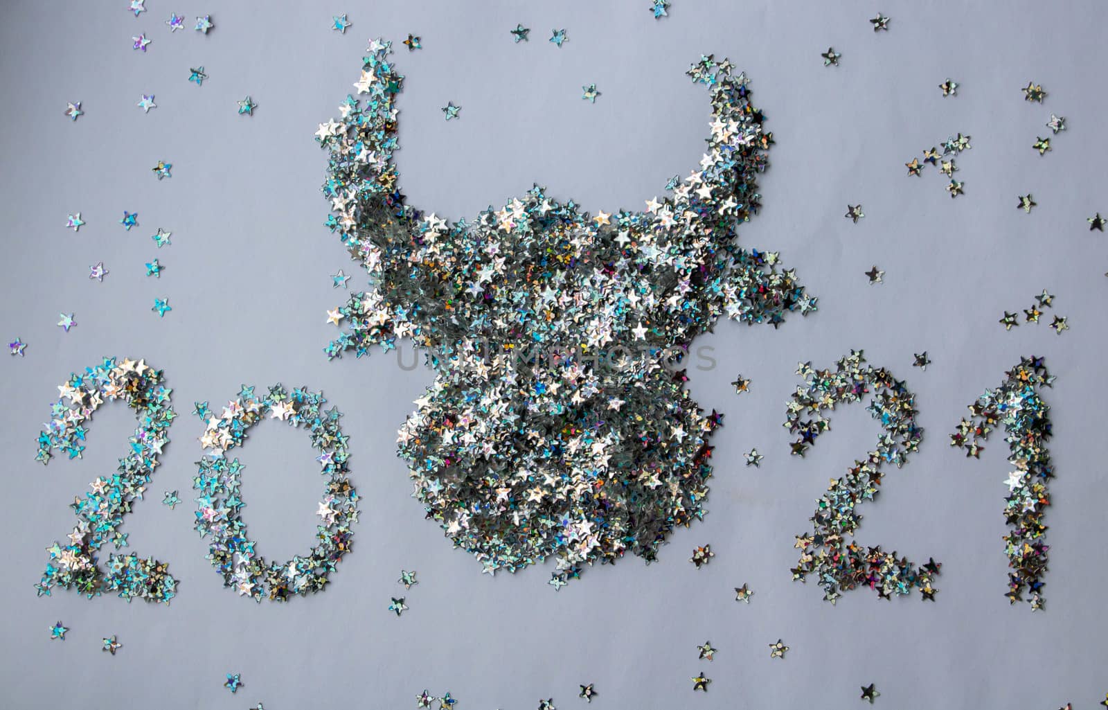 The bull and the numbers 2021 are made of silver glittering stars on a white background. decorations for a happy Christmas happy New year background design