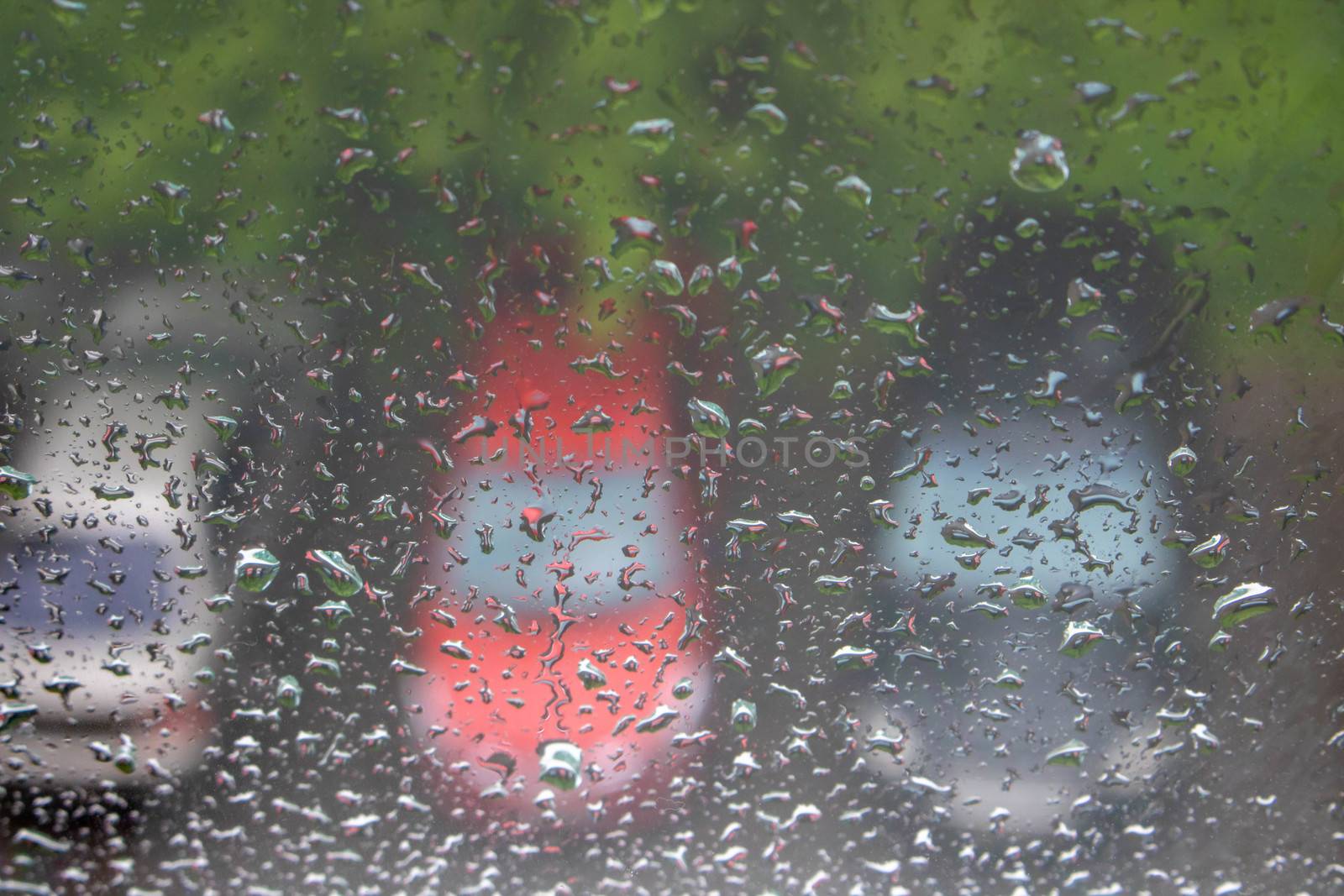Raindrops on the window, with cars in the Parking lot in the background by lapushka62