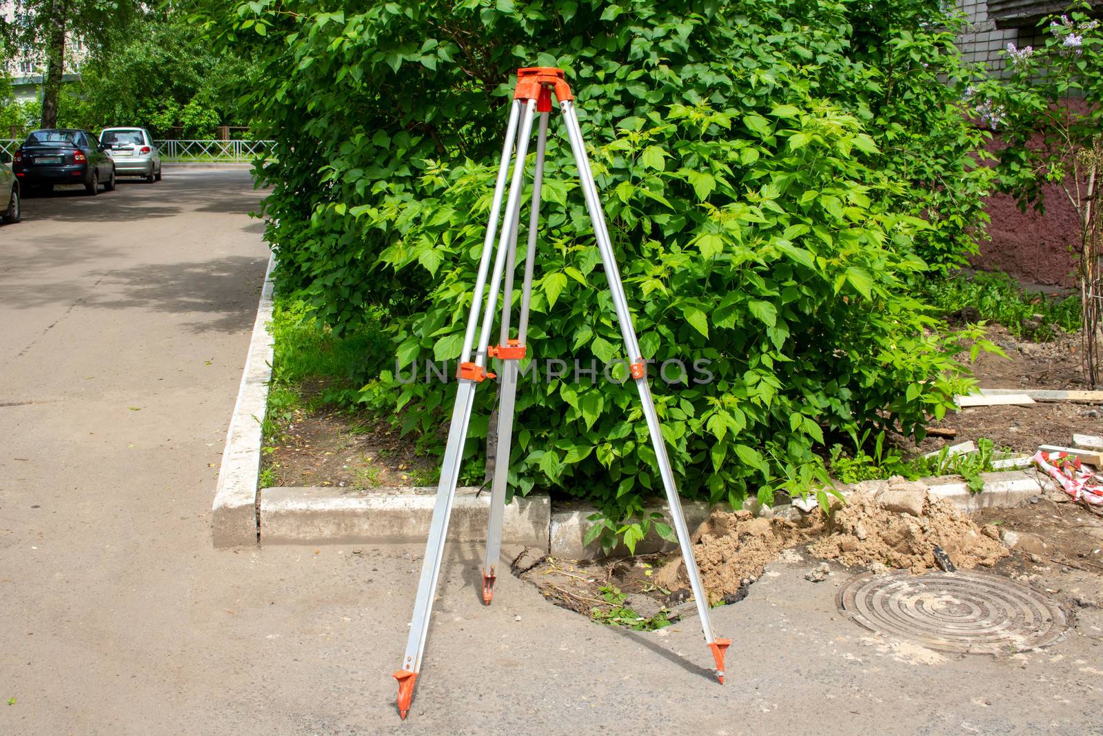 Surveyors equipment theodolite or total positioning station on the construction site of the road or building with construction machinery background.