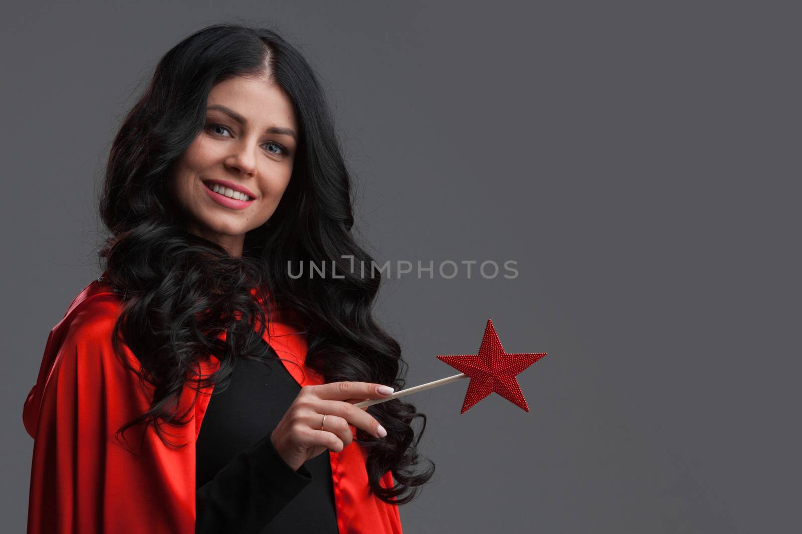 Woman with star shaped magic wand on gray background, halloween costume