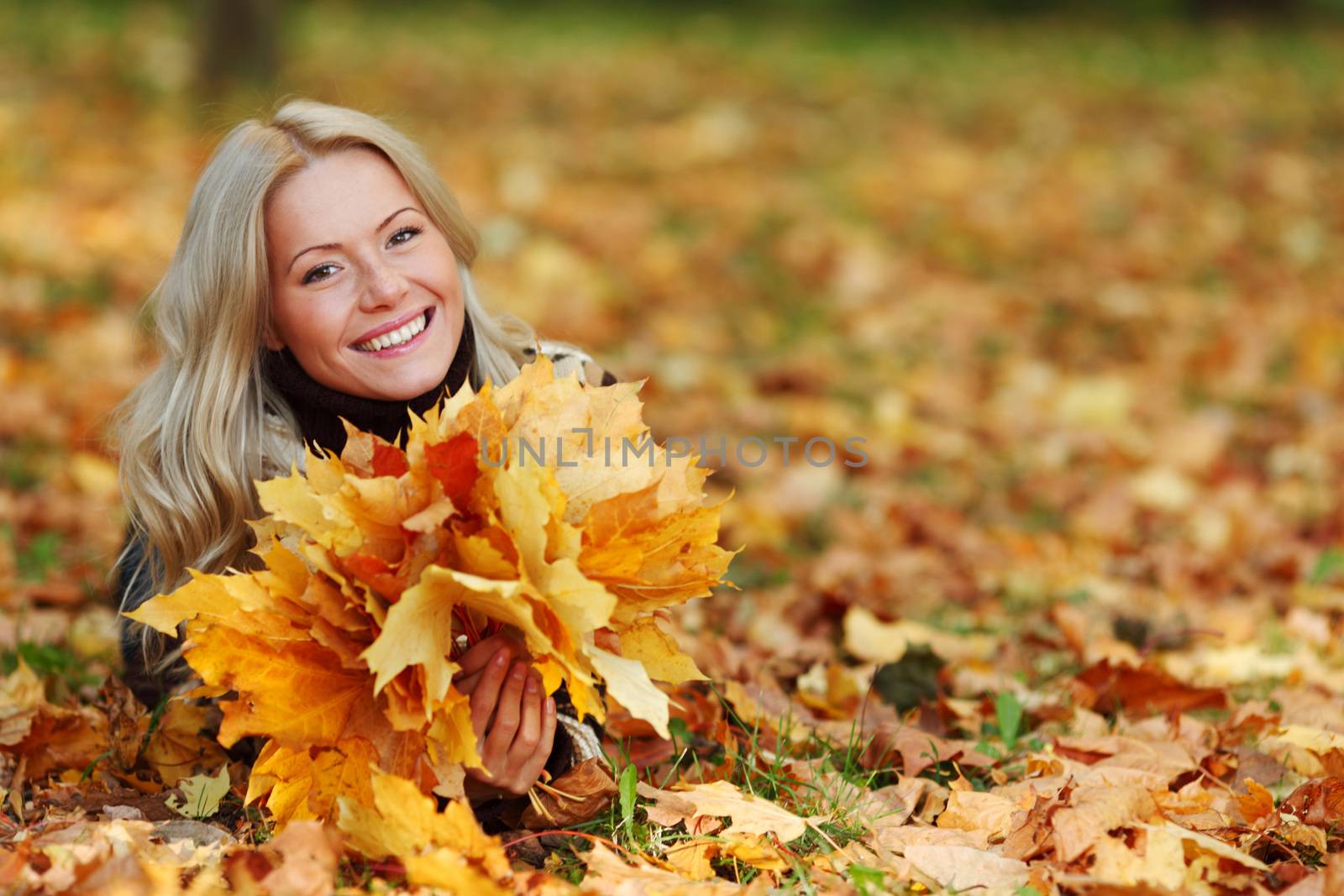 smiling woman portrait in autumn leaf holding bunch of leaves close up