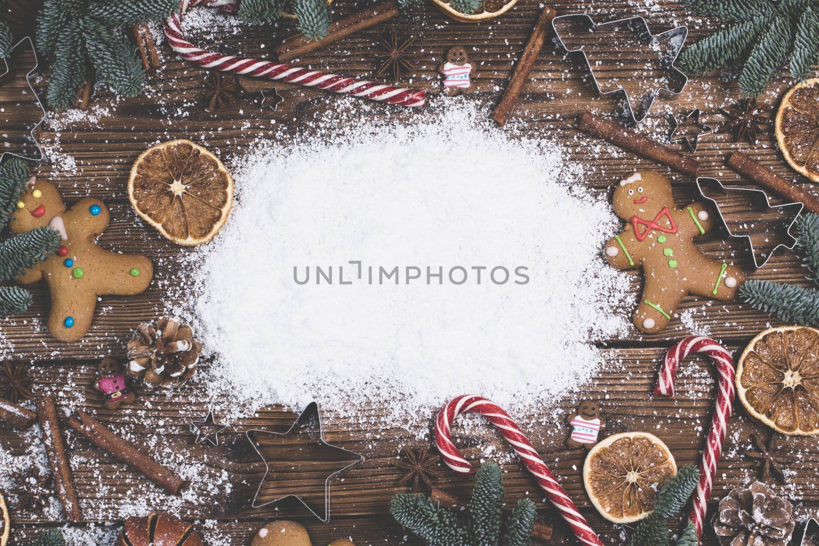 Christmas food frame. Gingerbread cookies, spices and decorations on wooden background with white copy space on snow