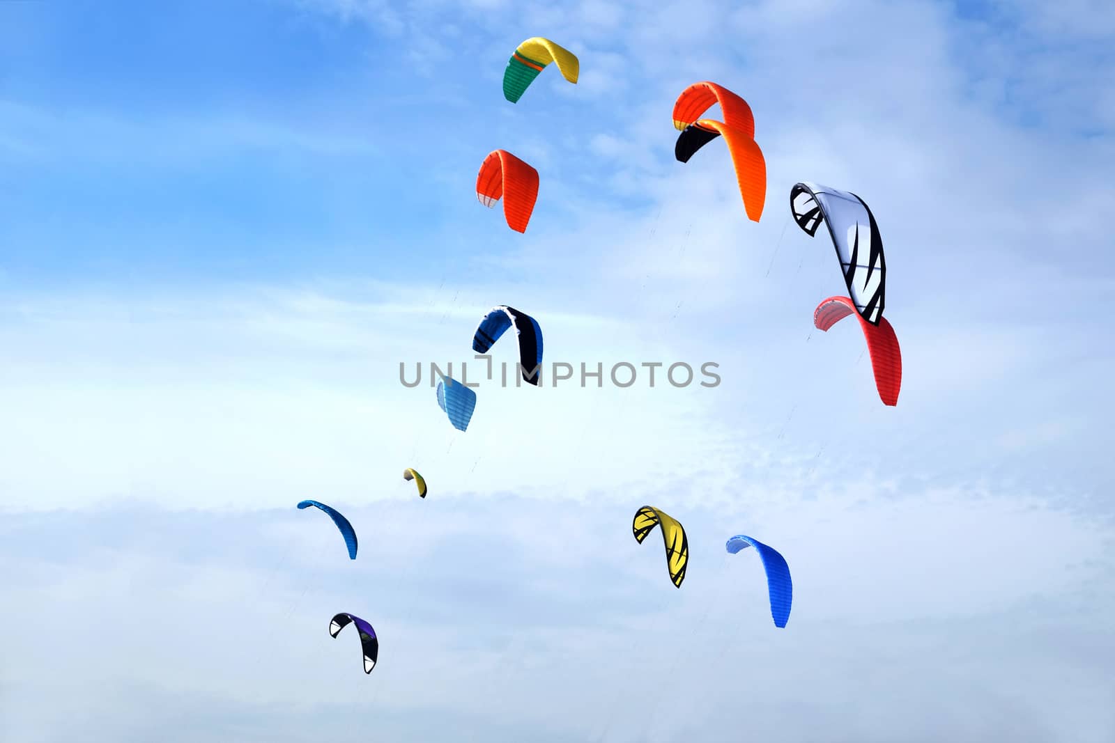 Many big colorful sport kites flying high in bright blue sky on bright sunny day by dymaxfoto