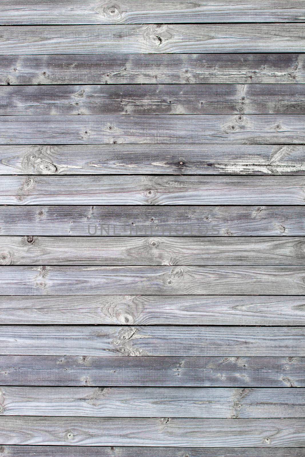 Wooden background made of old boards. The texture of an old rustic wooden fence made of flat processed boards. Wooden fence made of old boards with the inclusion of Knots. Background design
