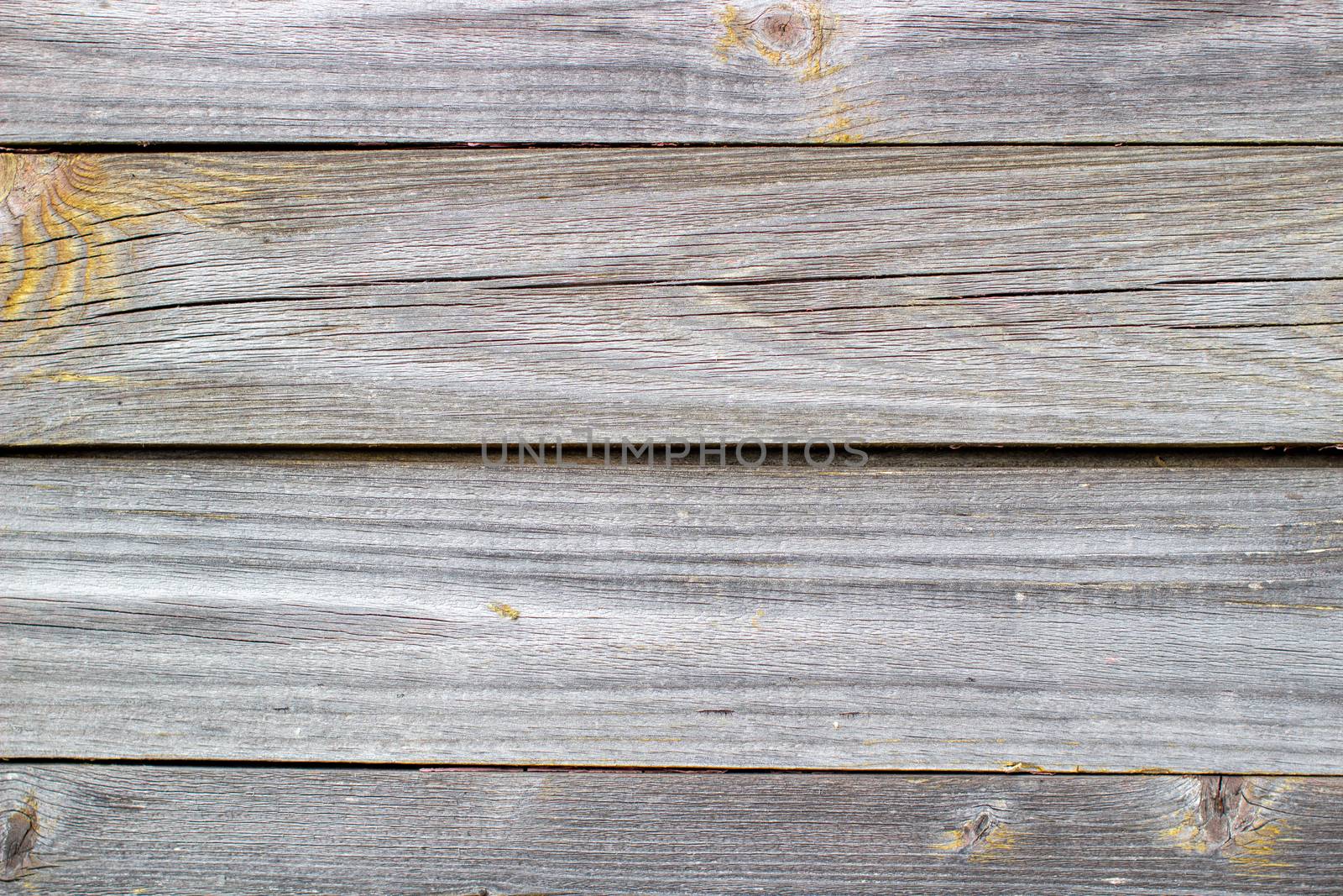 Wooden background made of old boards. The texture of an old rustic wooden fence made of flat processed boards. Wooden fence made of old boards with the inclusion of Knots. Background design