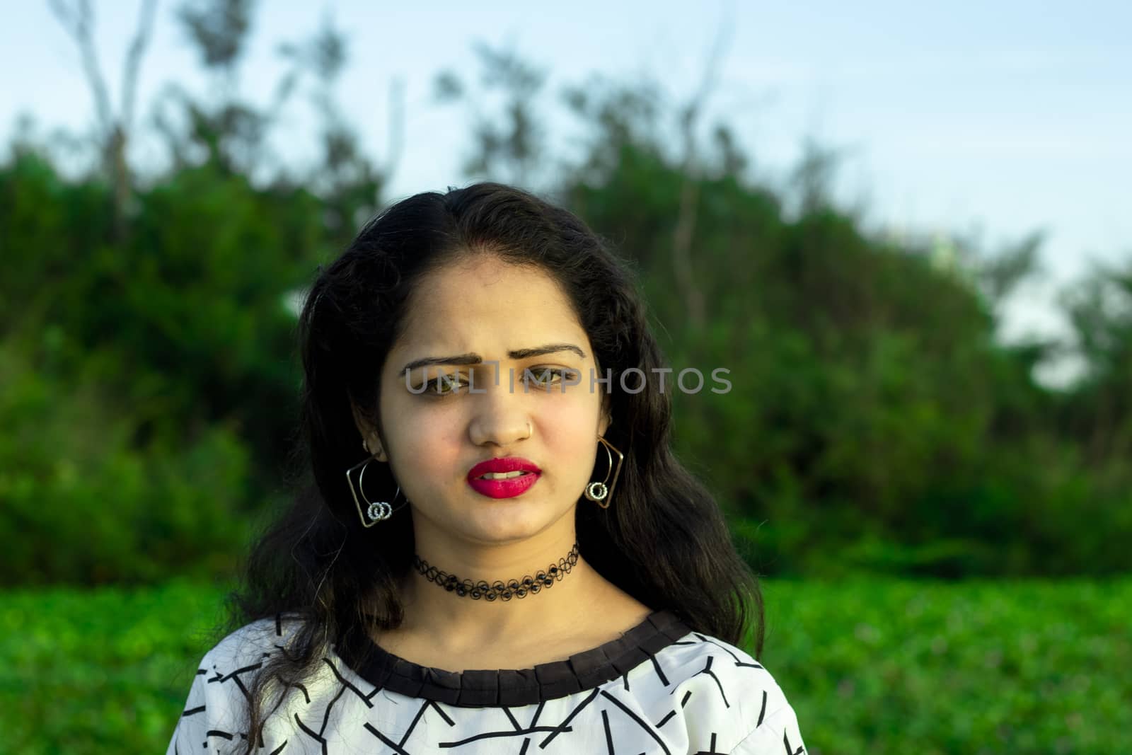 an indian model with closeup beautiful face and green blurred background of outside trees