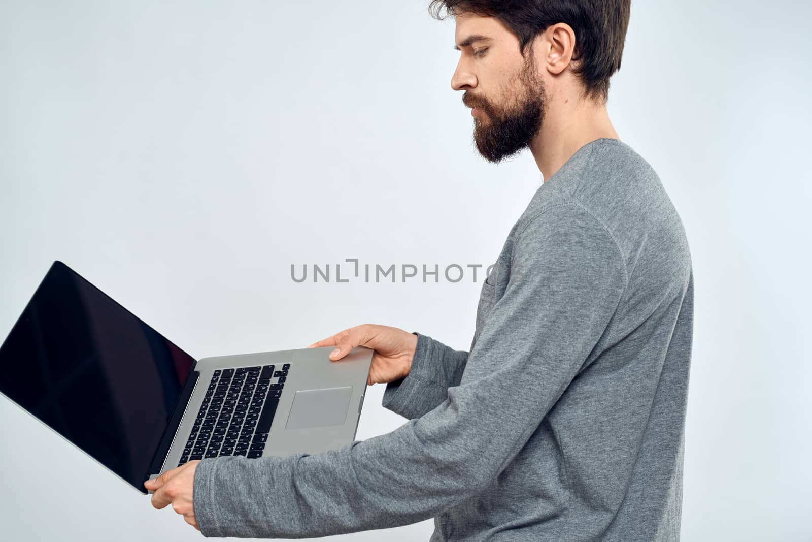 A man in a gray sweater with a laptop hands lifestyle technology communication internet work by SHOTPRIME