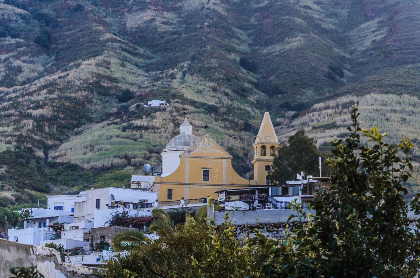 Village with the church of san vicenzo at the base of the volcano stromboli and the slopes of the same in the background