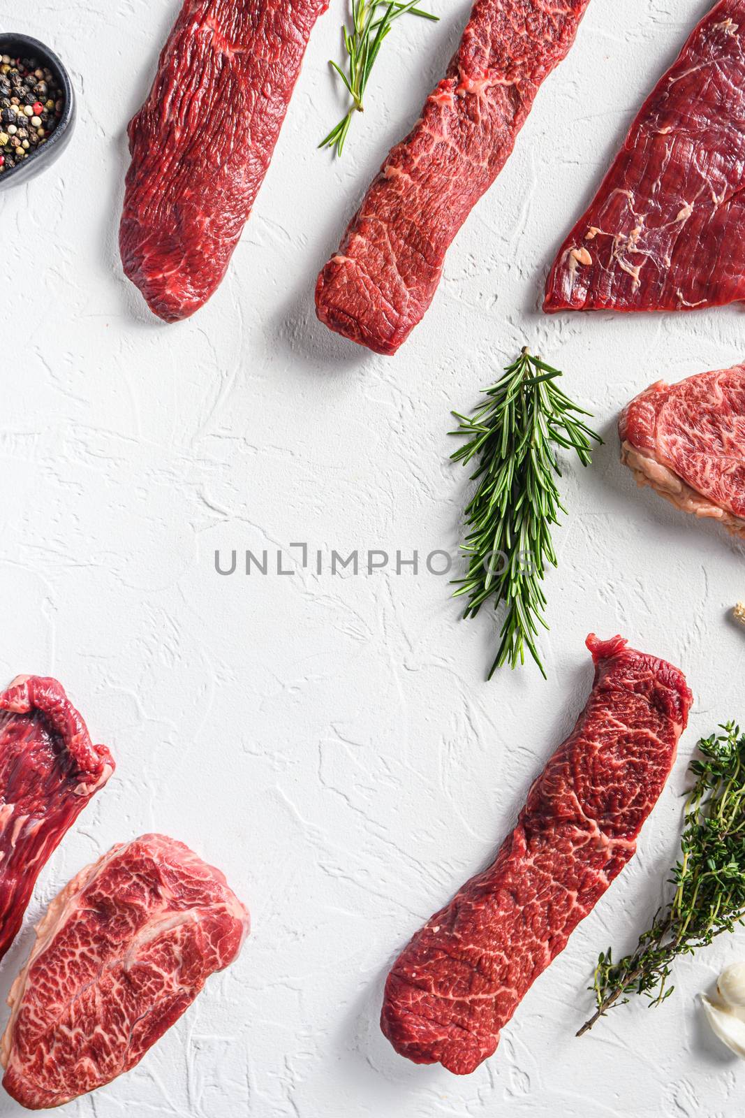 Set of different alternative types of raw beef steaks,on a white stone background top view concept frame in corners space for text in center vertical by Ilianesolenyi
