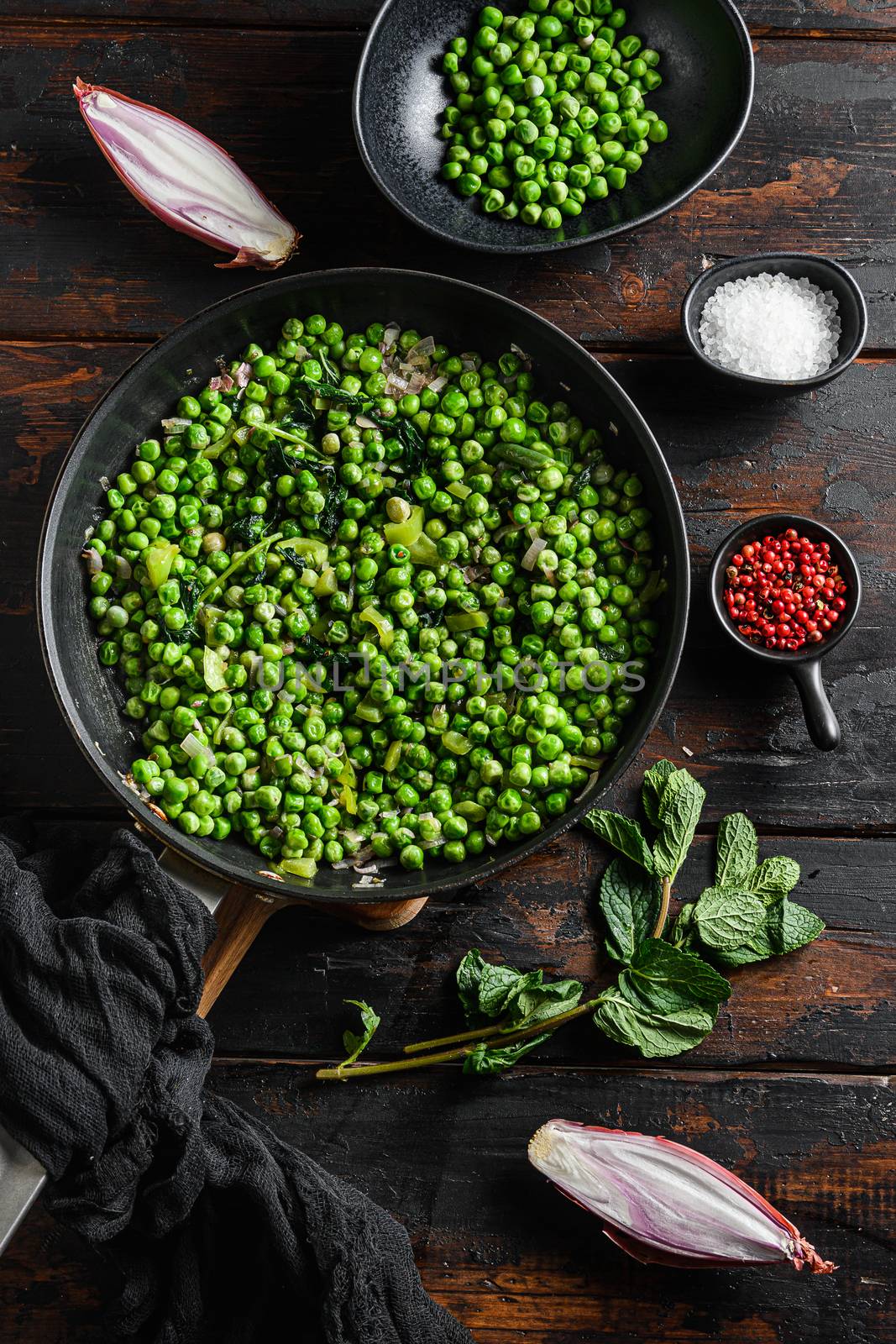 English mushy peas recipe in frying pan and peas in bowl with mint shallot pepper and salt top overhead view over old pub wood surface close up vertical by Ilianesolenyi