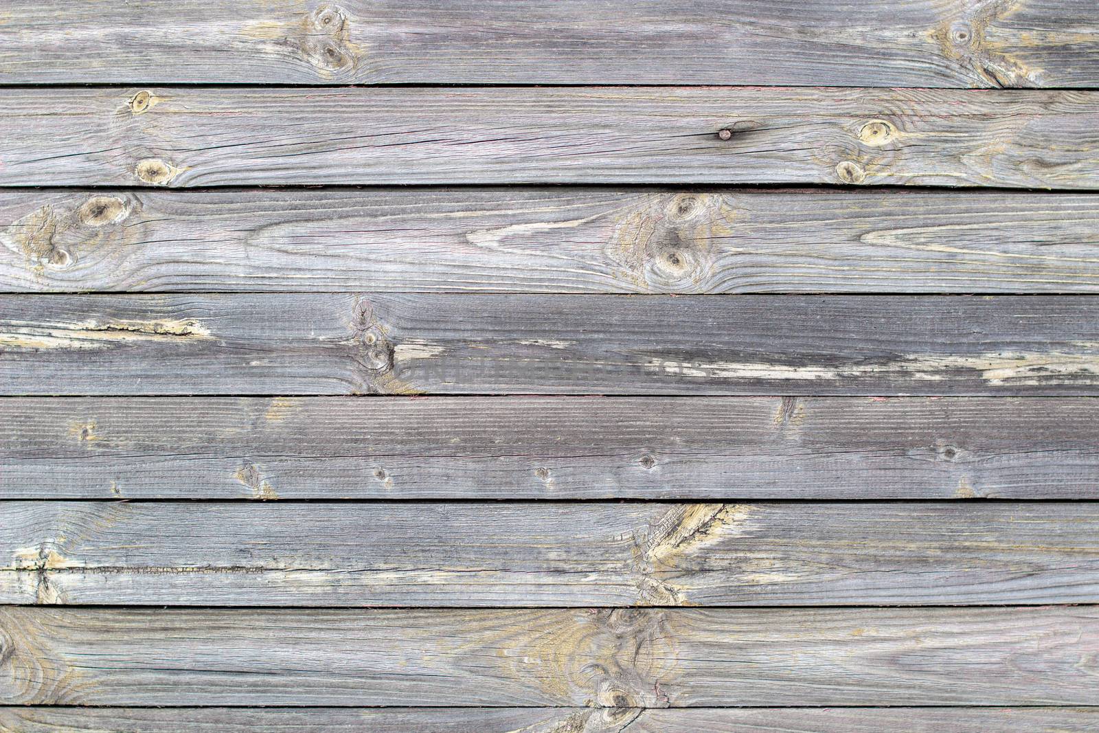 Wooden background made of old boards. The texture of an old rustic wooden fence made of flat processed boards. Wooden fence made of old boards with the inclusion of Knots. Background design
