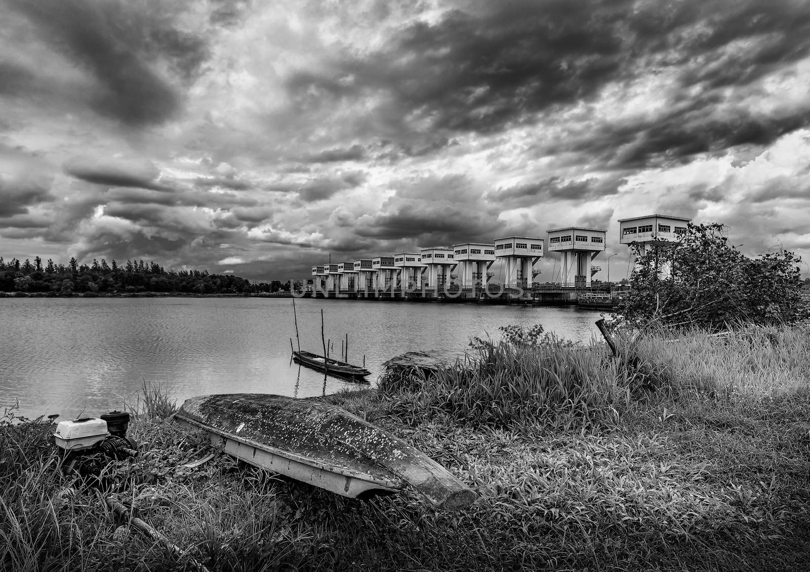 Fishing boat and water barrier and river with cloud sky storm in rain season, Black and white and monochrome style