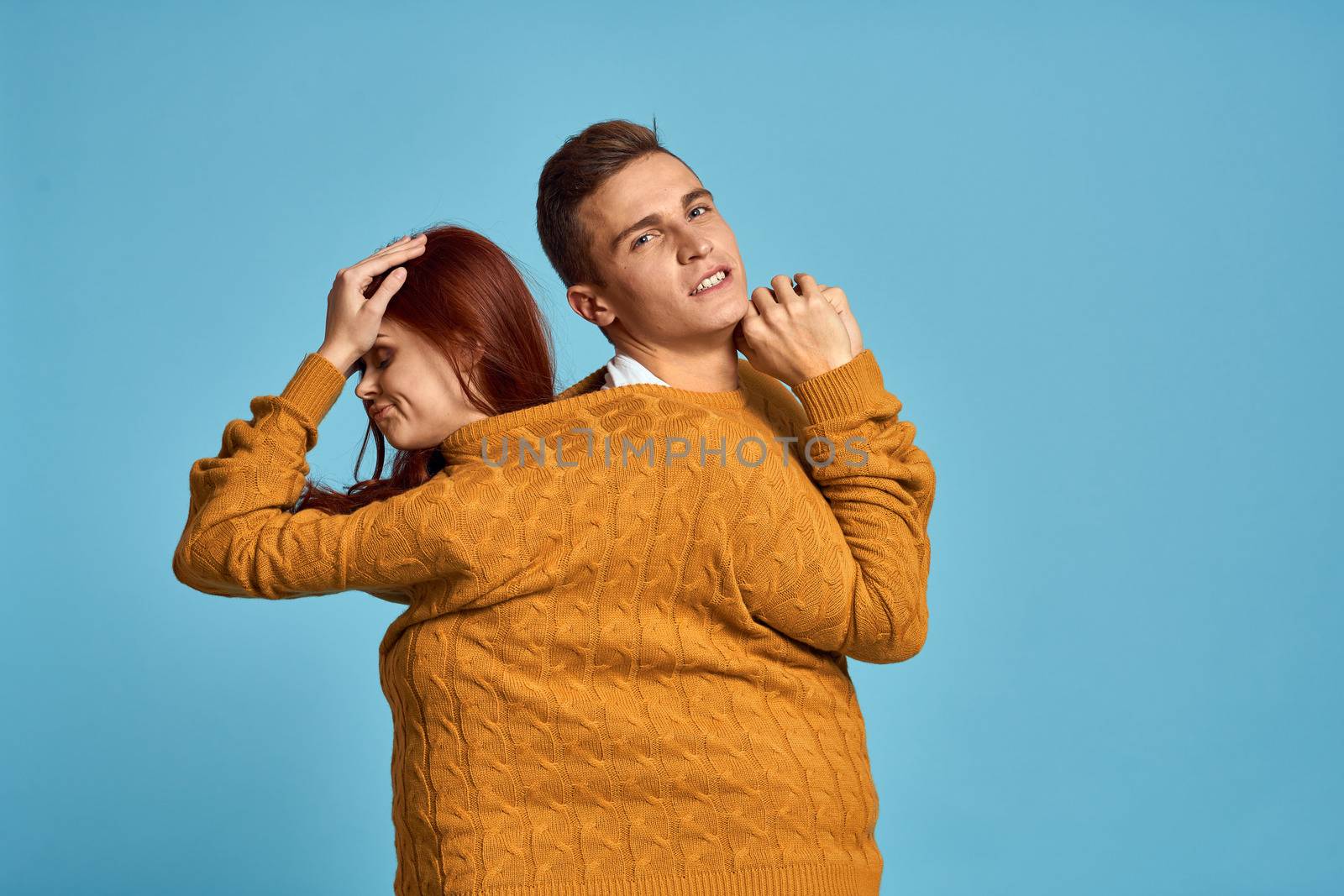 couple in yellow sweater posing against blue background cropped view by SHOTPRIME