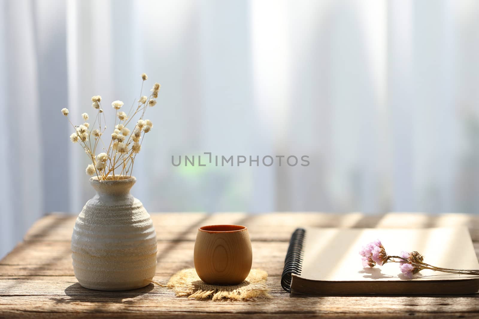 Dry flower in clay pot with notebook on and flower on rustic brown wooden table interior modern house decor