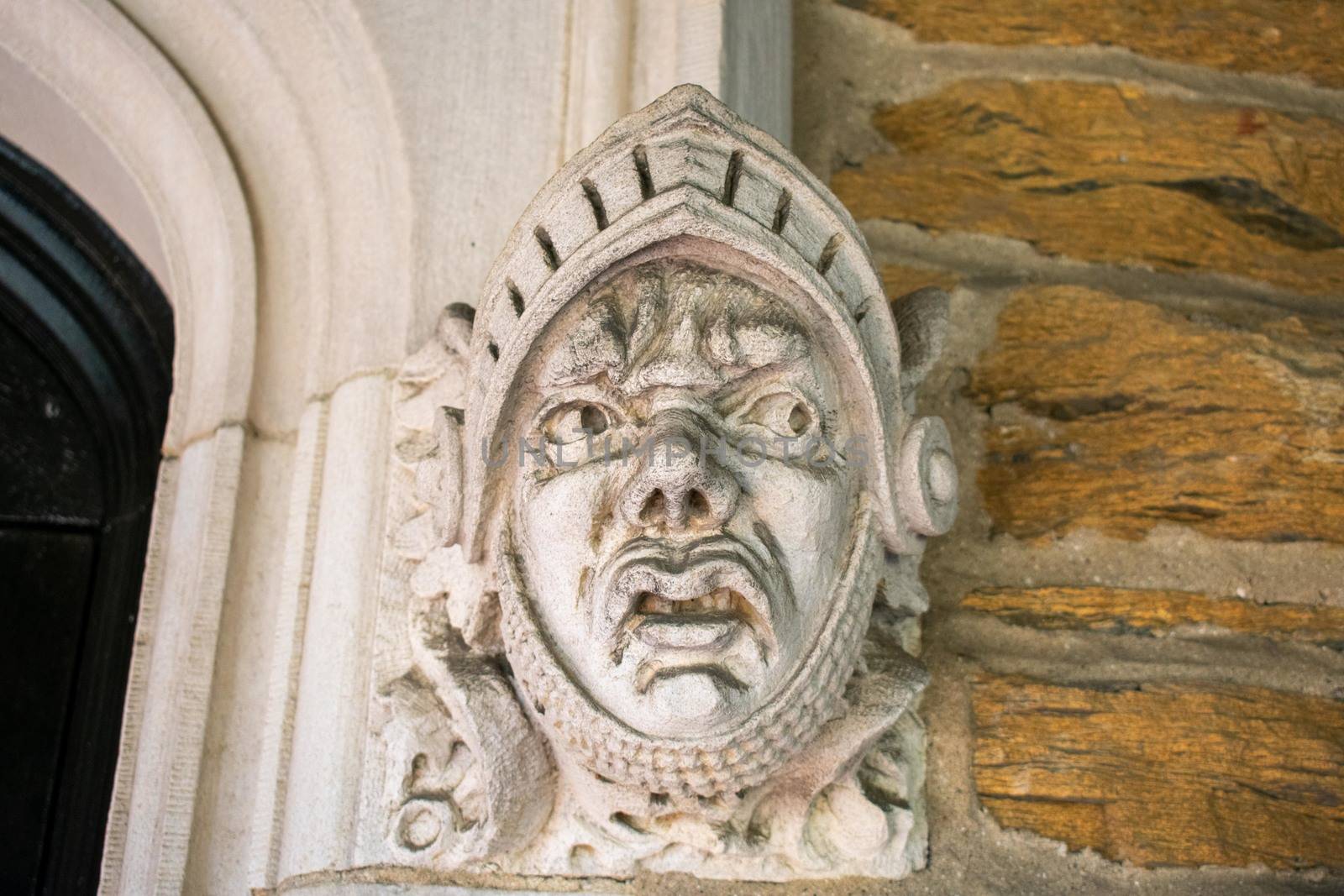 A Detailed Statue of a Face on a Cobblestone Wall at the Elkins  by bju12290