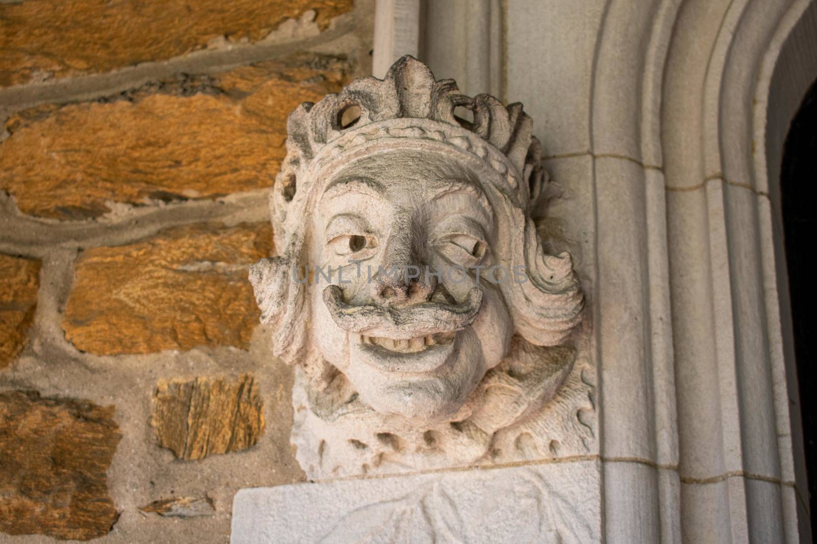 A Detailed Statue of a Face on a Cobblestone Wall at the Elkins  by bju12290