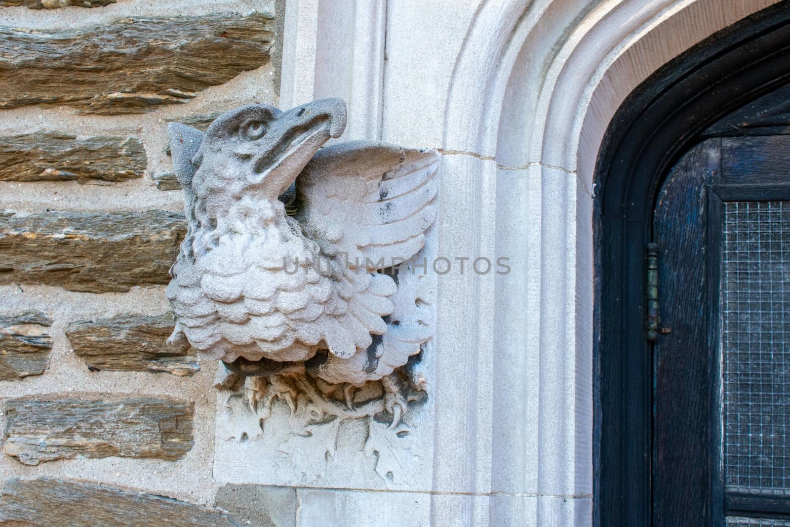 A Statue of a Griffin Sticking Out of a Cobblestone Wall Next to a Doorway at the Elkins Estate