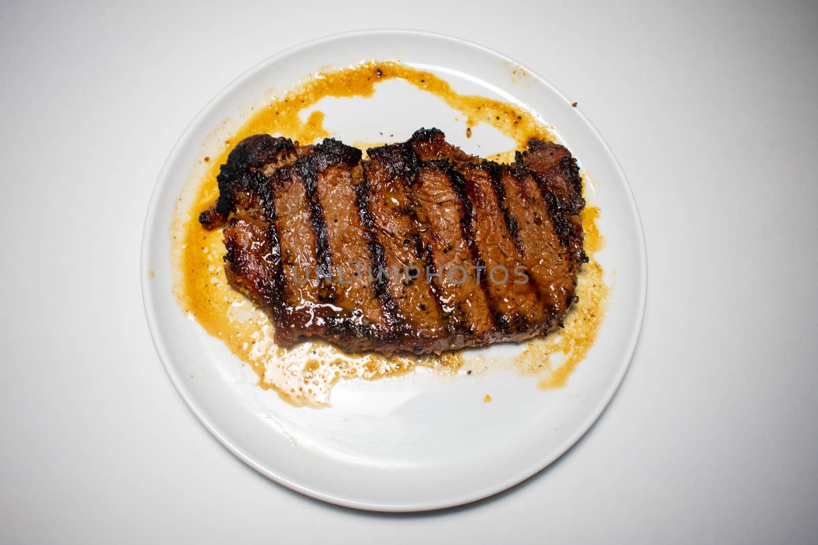 A Perfectly Cooked Steak With Grill Lines Plated on a Pure White Background