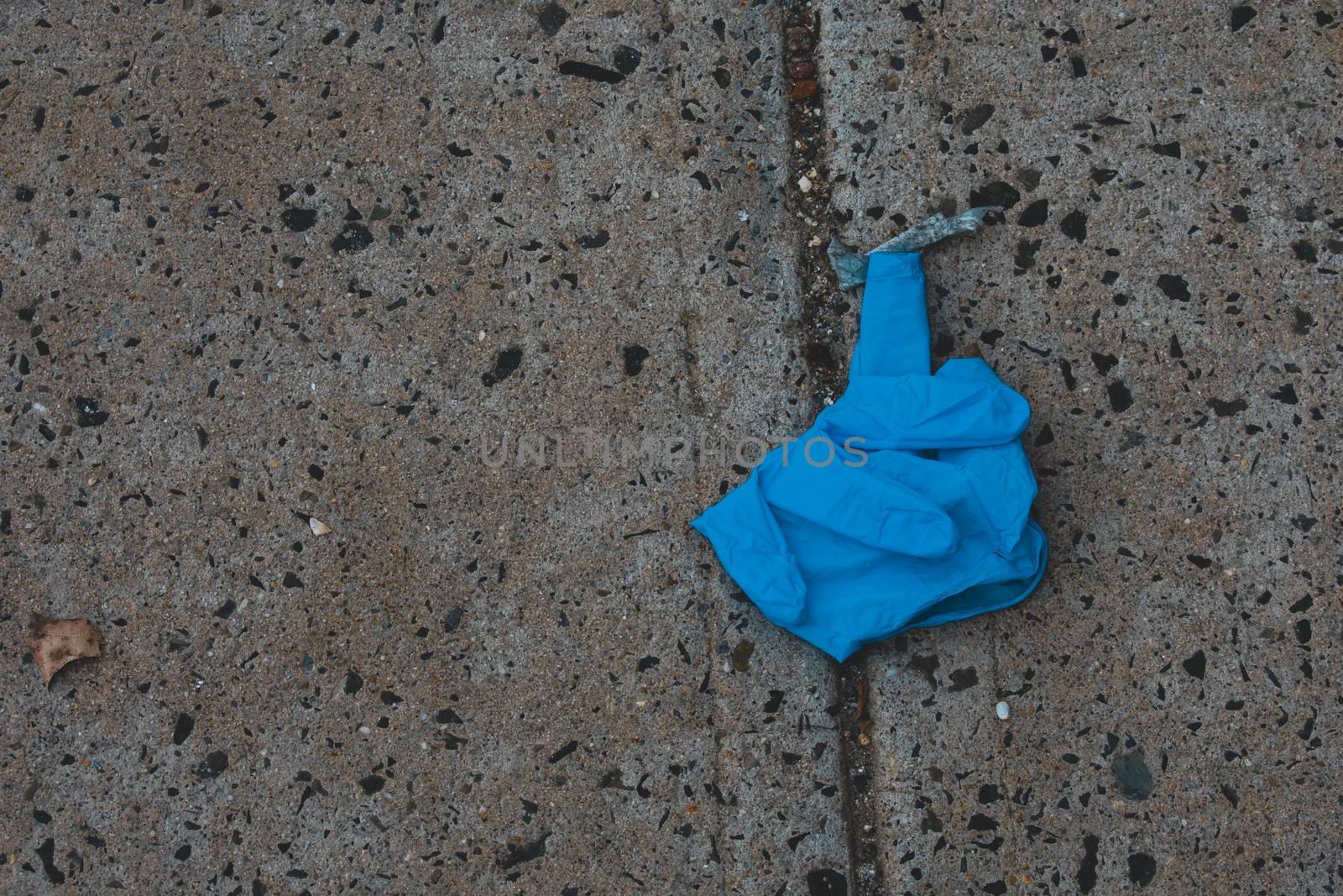 An Old Blue Medical Glove on the Ground Used to Protect From COVID-19