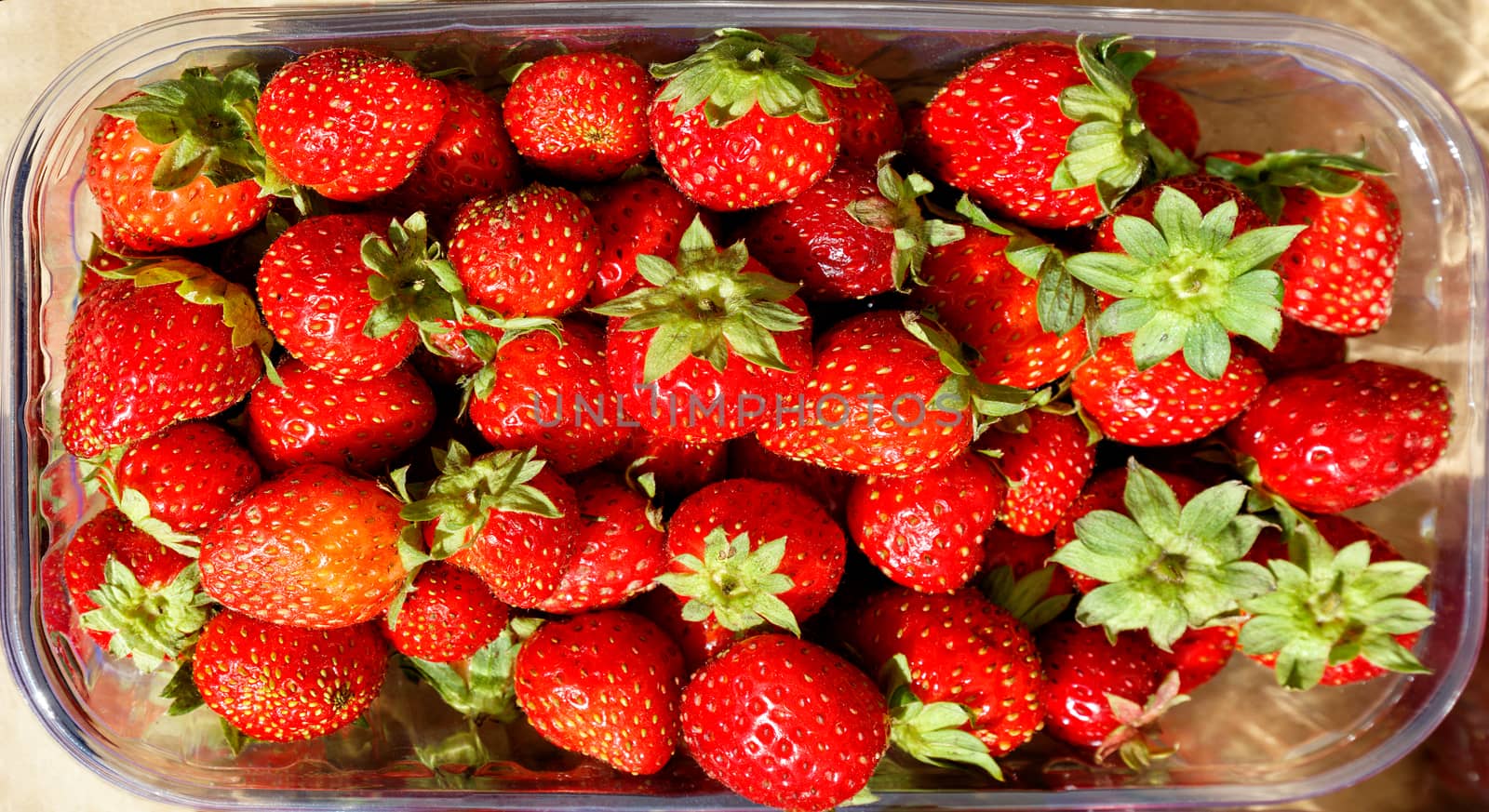 Red ripe strawberries lie in plastic containers and are sold in street markets, top view.