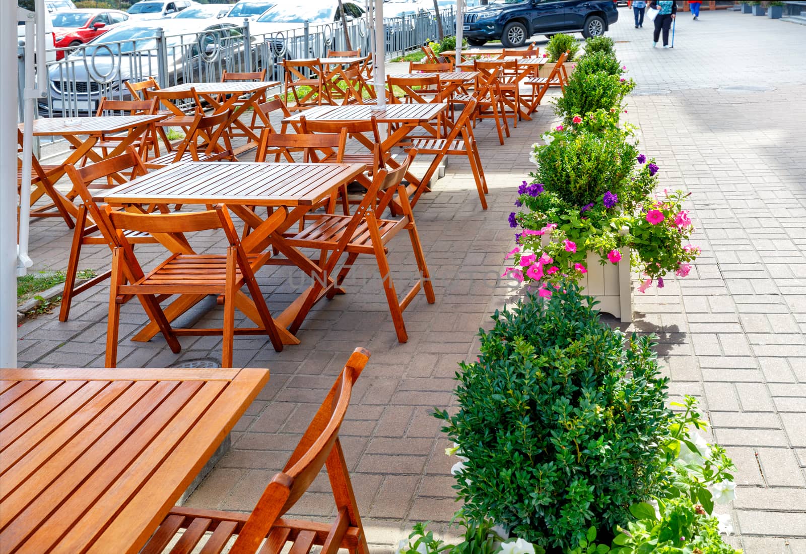 A deserted city street cafe, empty tables and chairs on the sidewalk under a canopy. by Sergii