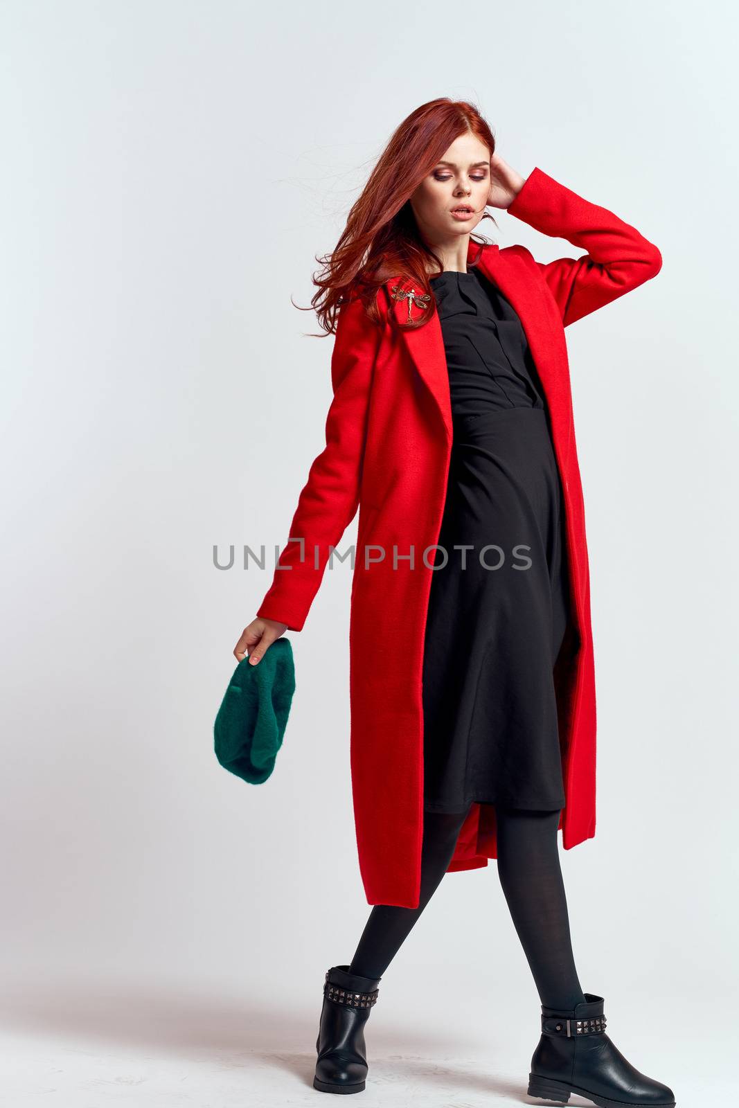 emotional woman in a red coat and with a hat in full growth on a light background black boots pose model by SHOTPRIME