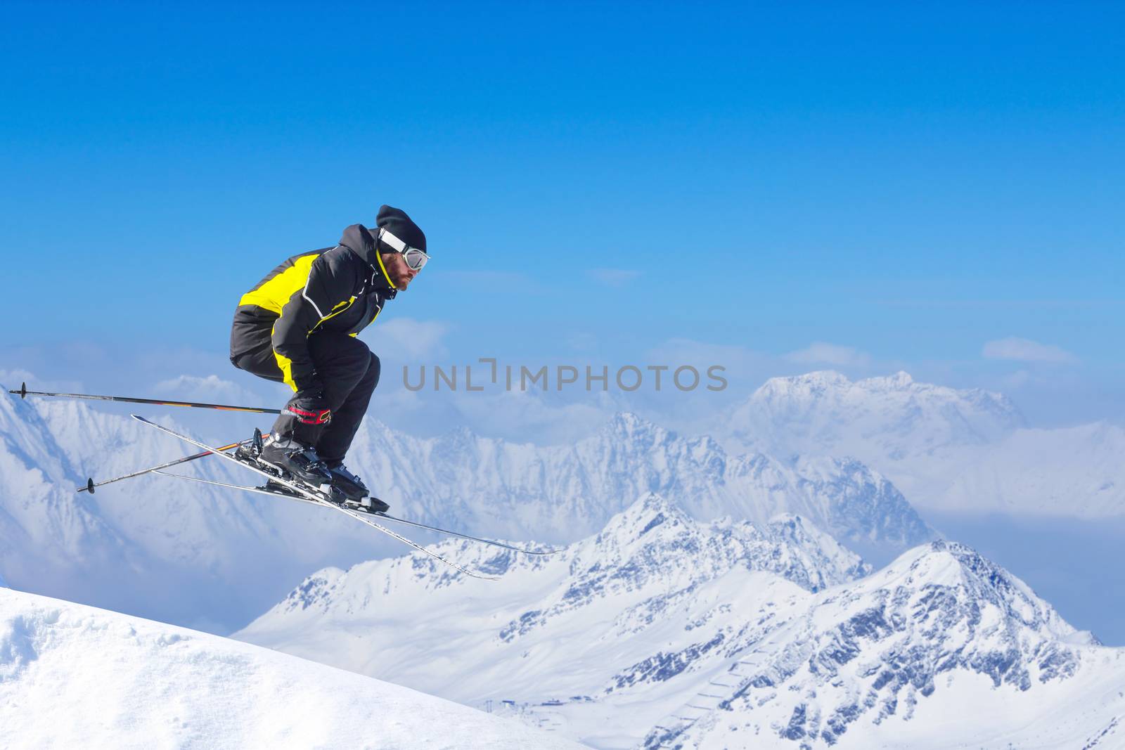 Jumping skier at jump with alpine high mountains copy space for text