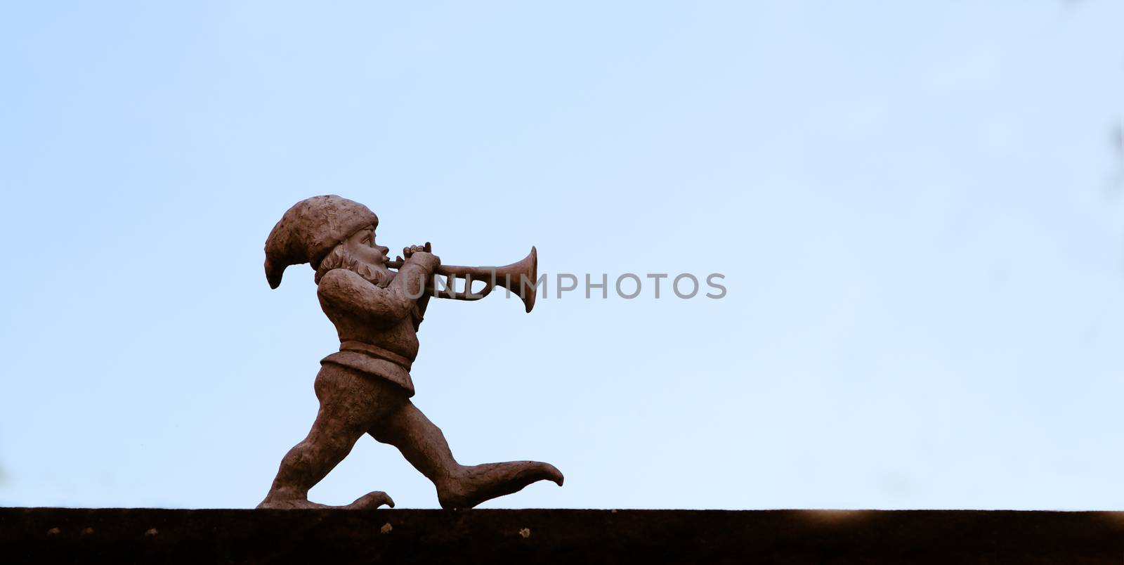 dwarf playing a trumpet in front of blue sky
