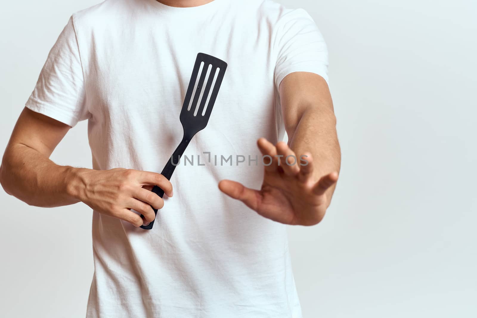 man with shovel for cooking white t-shirt cropped view light background. High quality photo