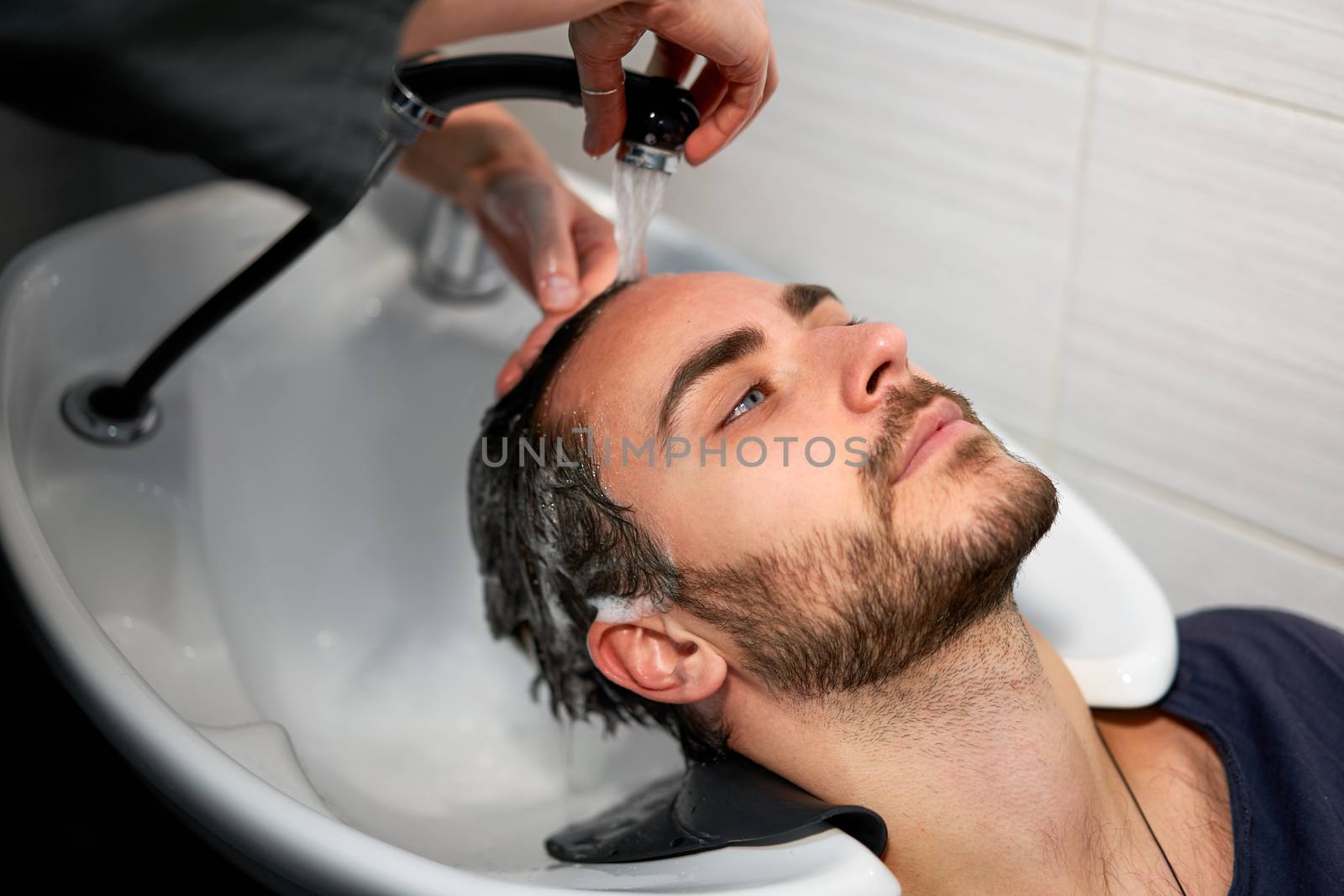 Woman applying shampoo massaging hair customer Man wash hair in beauty salon Hairdresser washing hair. Happy caucasian guy enjoy service in barbershop Preparing the client before hairdressing