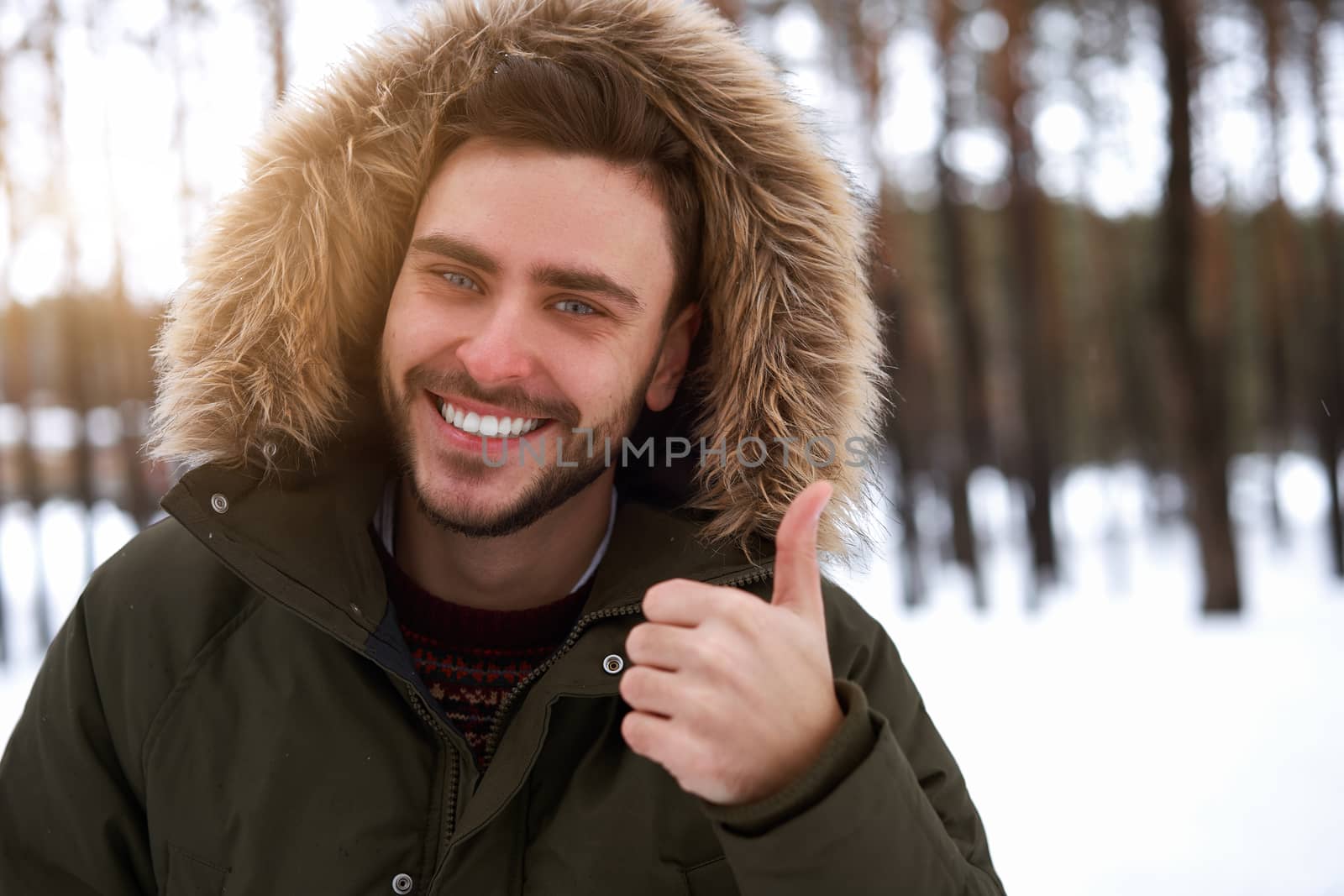 Handsome bearded young caucasian man standing outdoors sweater winter season forest. Attractive stylish european guy walking snowy christmas woodland Season holiday leisure Showing thumbs up gesture