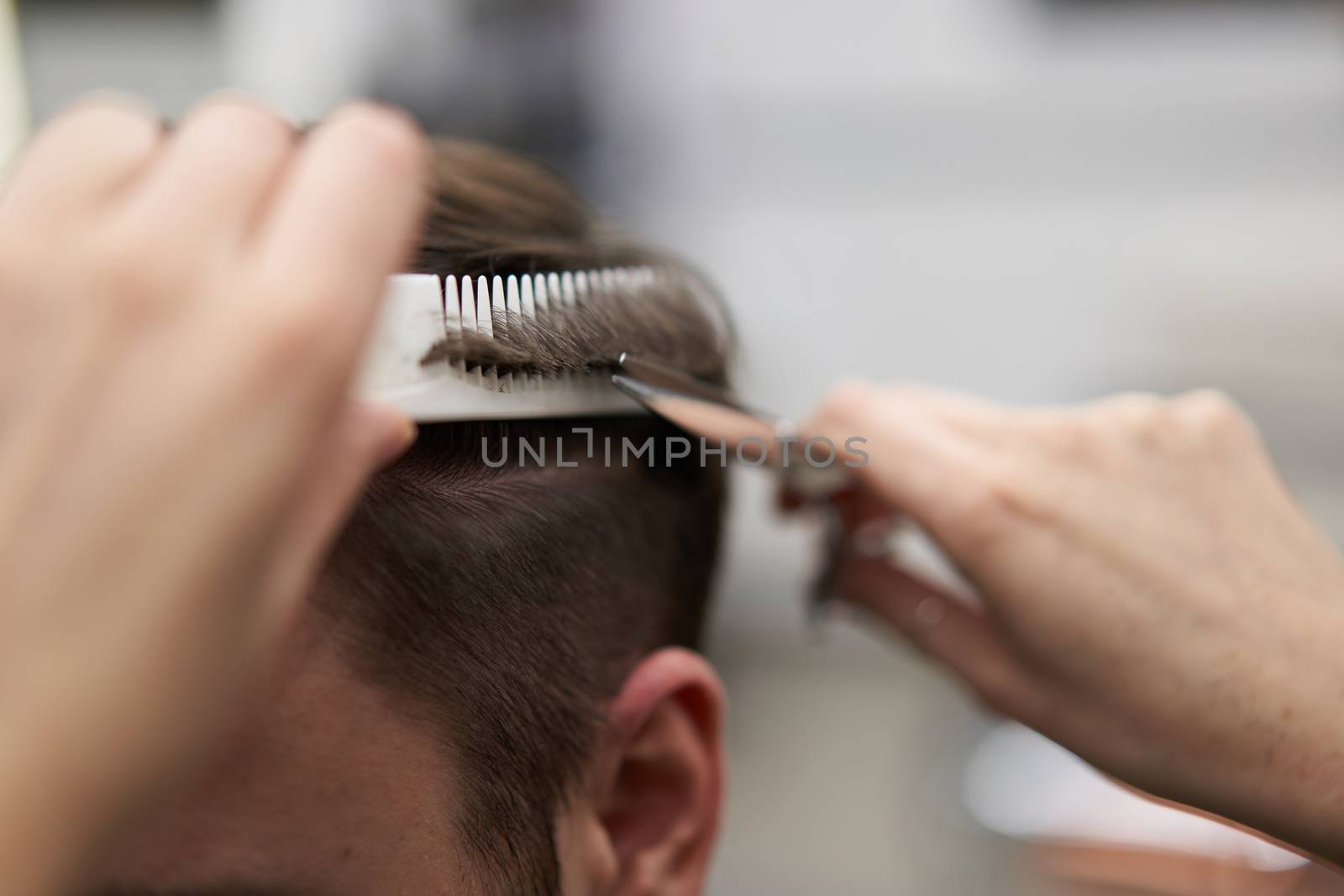 Beautiful caucasian woman hairdresser doing hairstyle to client. Close up portrait female barber with hairdressing tools at work. hair cutting process Hairstyling in modern barbershop. Professional