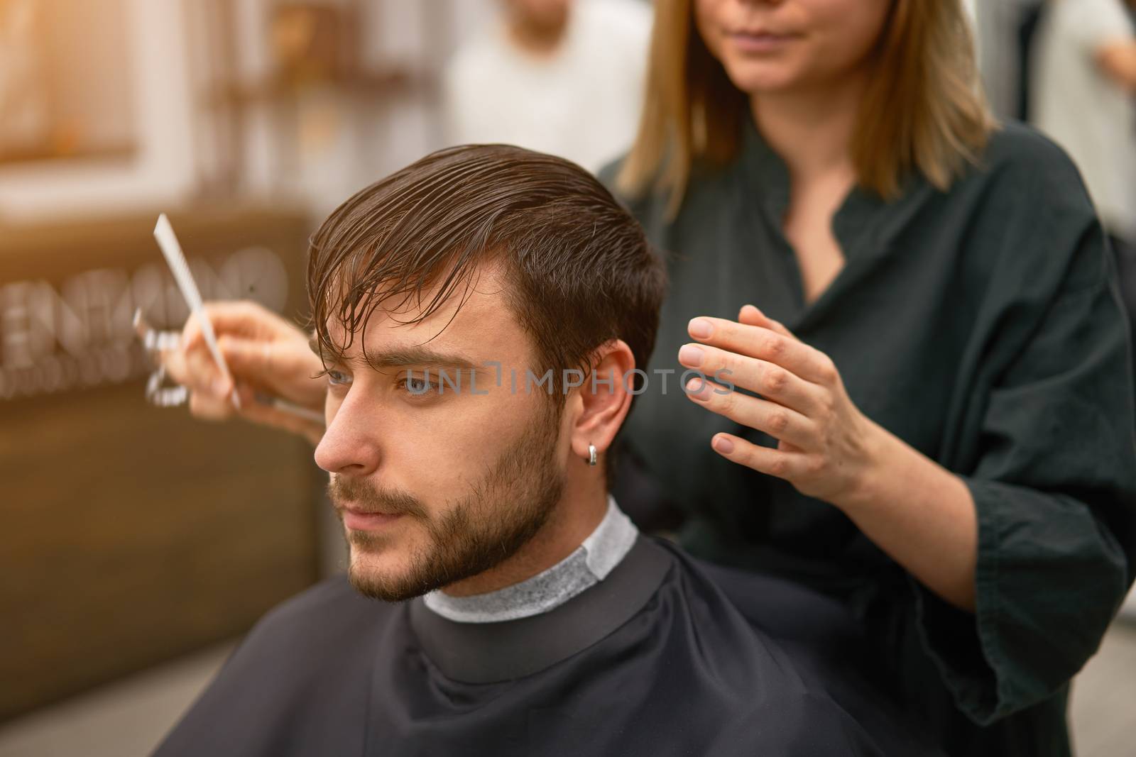 Stylish man sitting barber shop Hairstylist Hairdresser Woman cutting his hair Portrait handsome happy young bearded caucasian guy getting trendy haircut Attractive barber girl working serving client