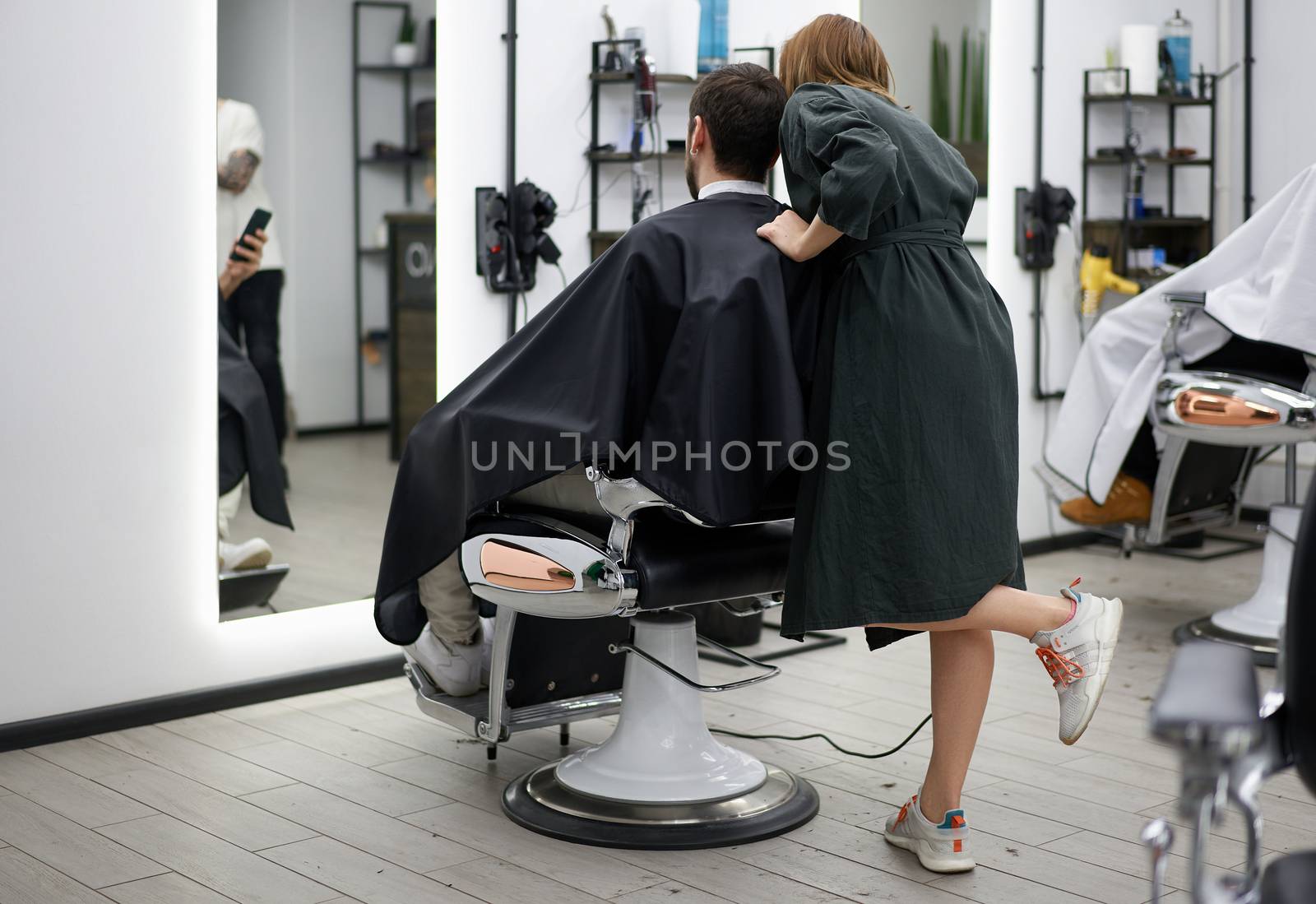 Stylish man sitting barber shop Hairstylist Hairdresser Woman cutting his hair Portrait handsome happy young bearded caucasian guy getting trendy haircut Attractive barber girl working serving client