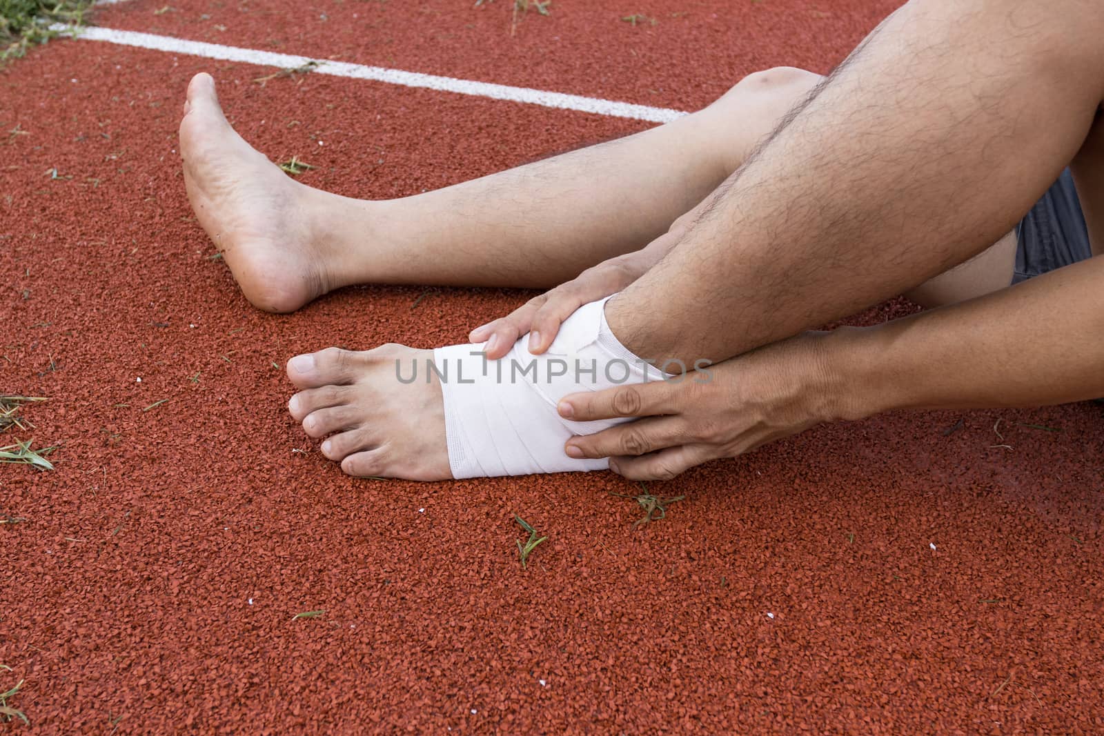 man applying compression bandage onto ankle injury of a football player, Sports injuries, concept First aid for ankle injuries