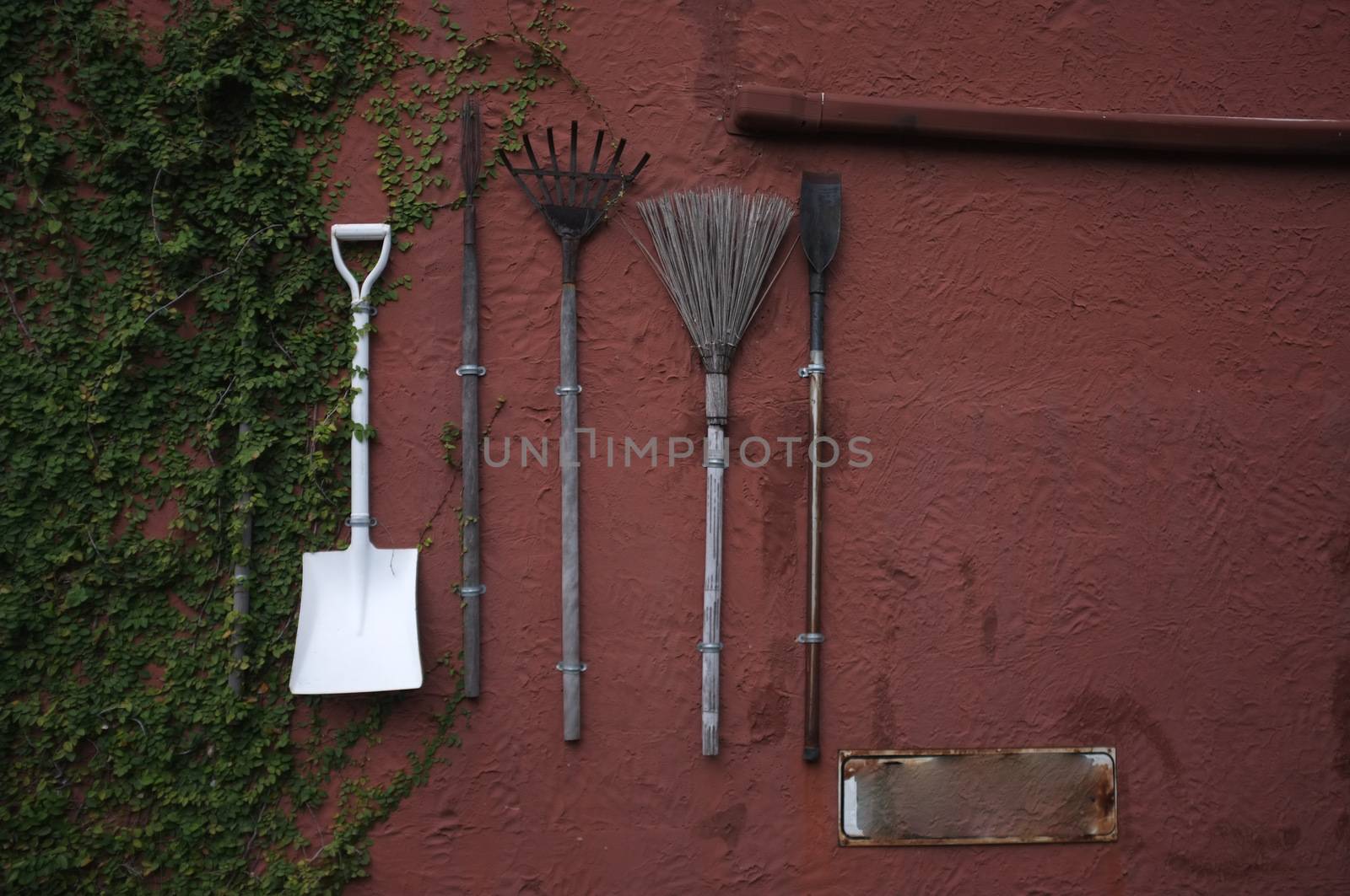 The gardening tools hanging on red cement wall.