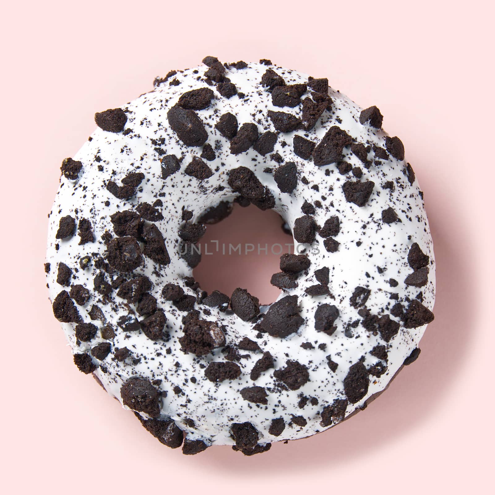 chocolate donut with white glaze isolated on pink background, close up flat lay