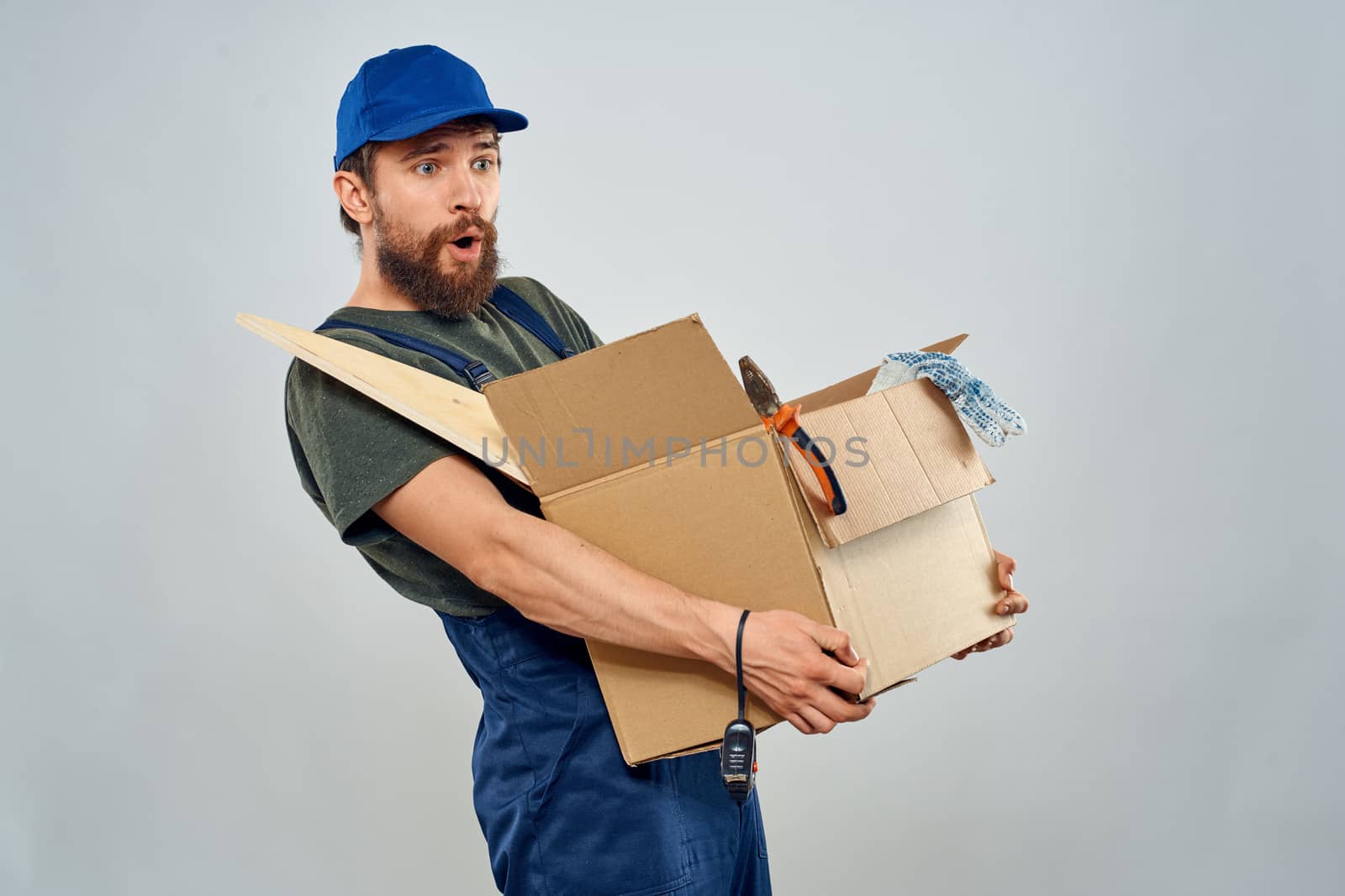 man in work uniform with box in hands tools lifestyle light background. High quality photo