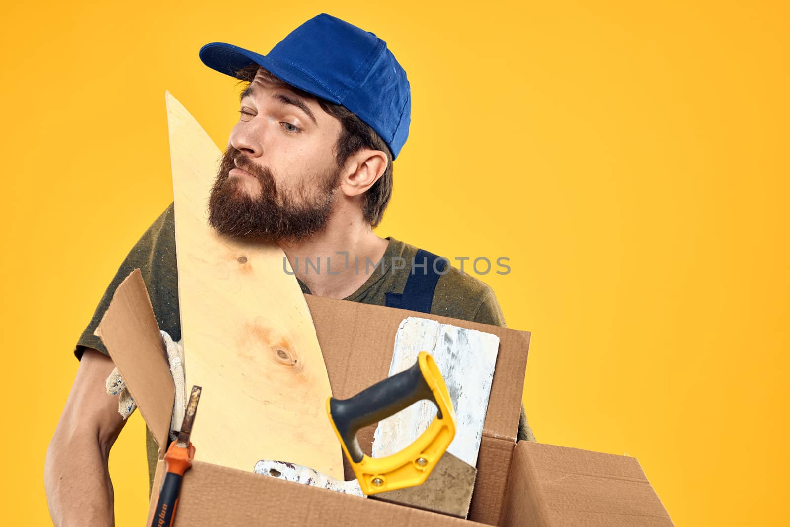 A man in a working form a box with loading tools yellow background. High quality photo